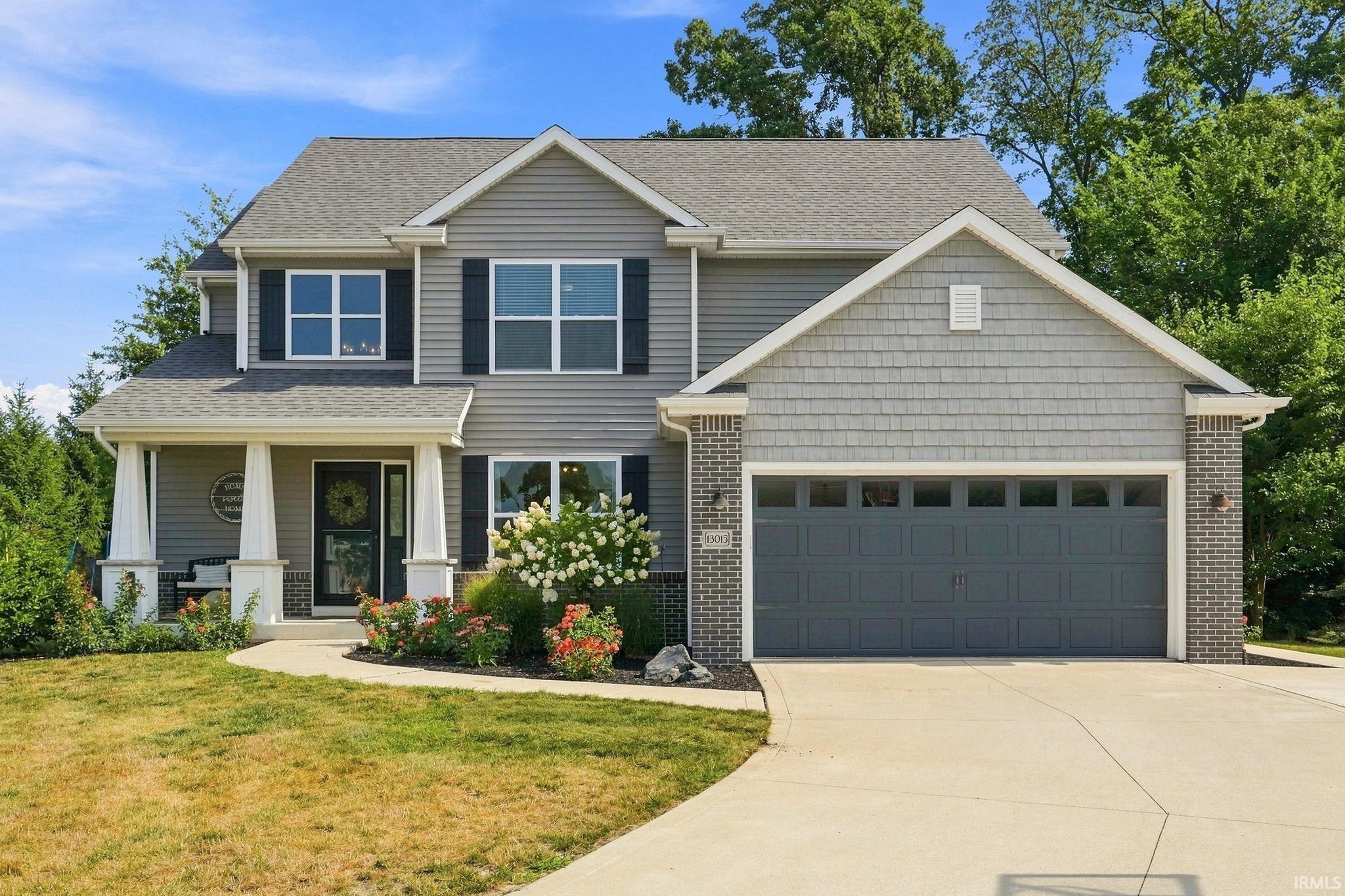Two-story residence featuring a covered front porch, a two-car garage, and a concrete driveway