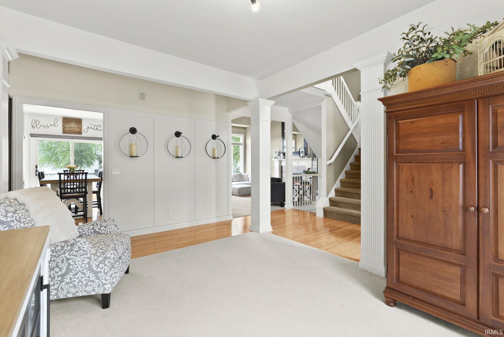 Entryway featuring white carpeting and a paneled wall with decorative sconces