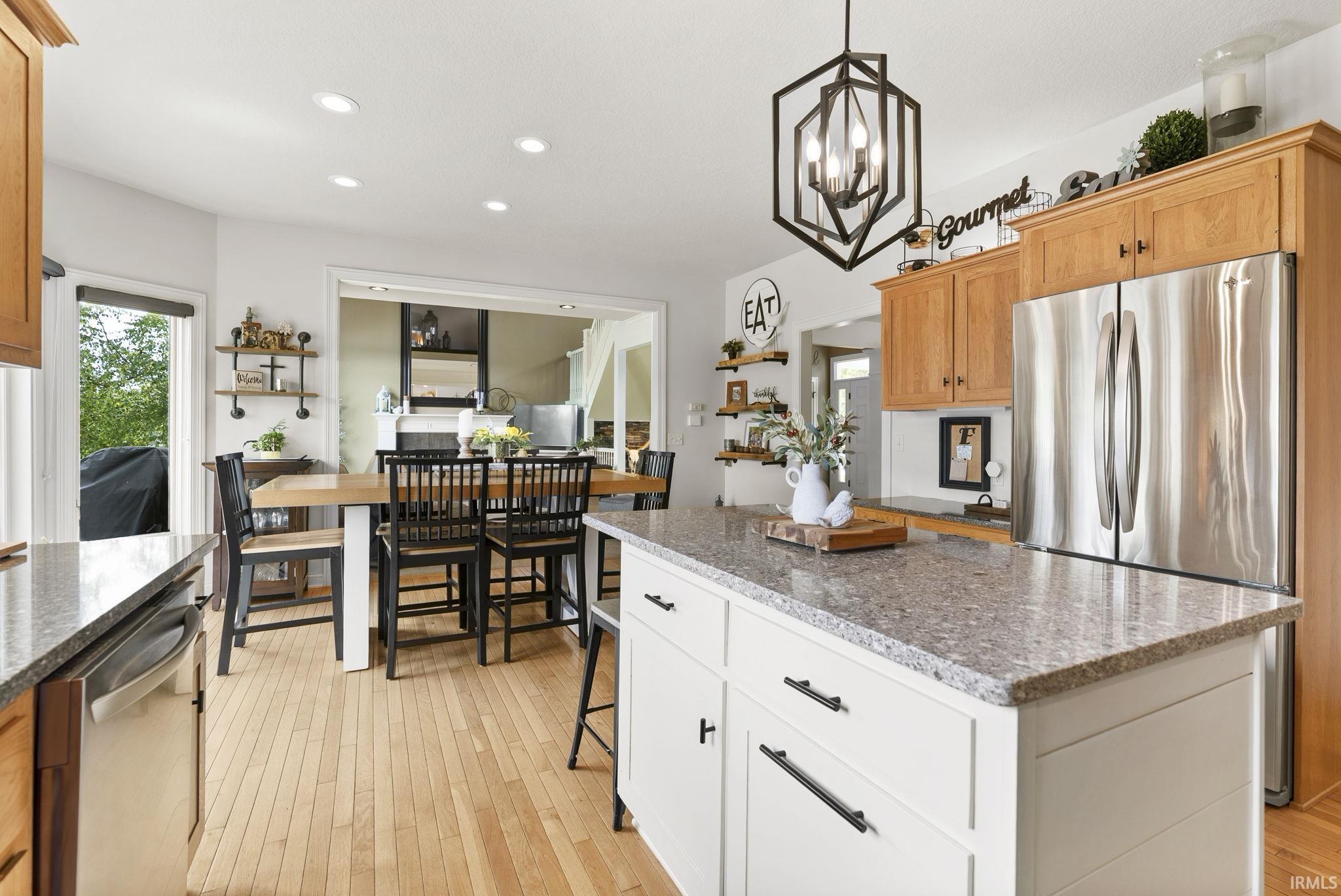 Modern kitchen featuring a central island with a speckled countertop, a stainless steel refrigerator, and wood-finish flooring