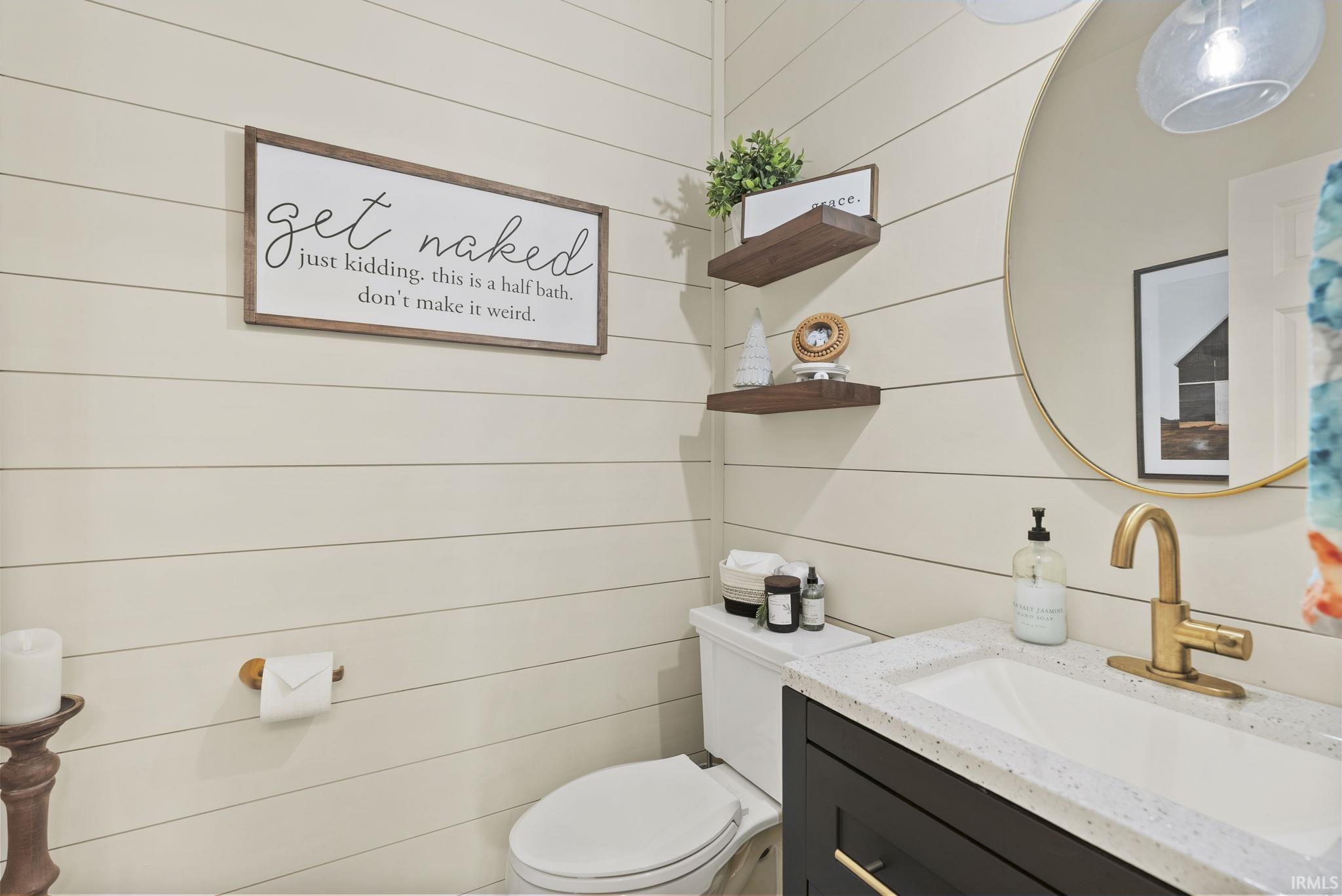 Shiplap wall paneling highlighting a vanity with a white countertop and integrated sink
