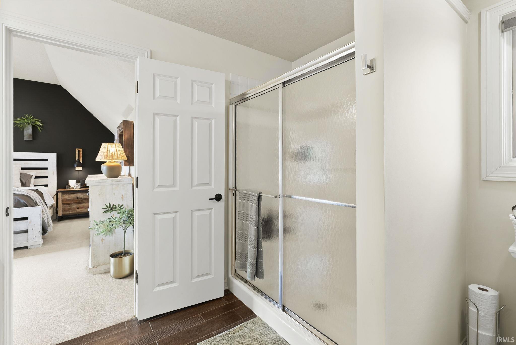 Bathroom featuring wood-finish flooring and a shower with frosted glass sliding doors