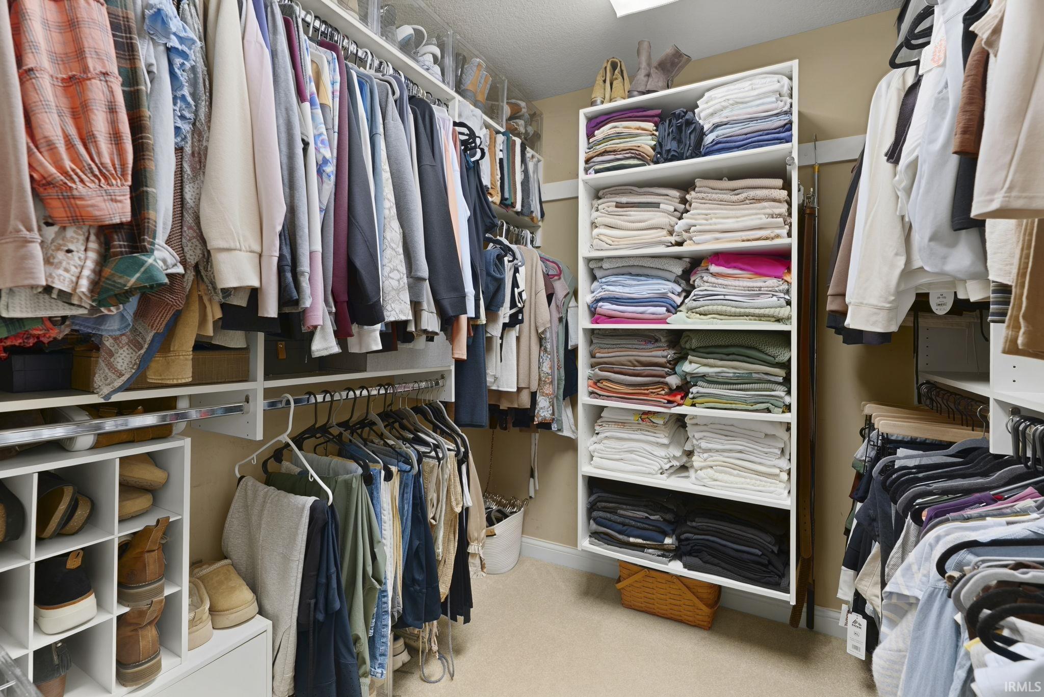 Custom closet system featuring extensive hanging rods, multiple shelving units, integrated shoe storage, and overhead storage