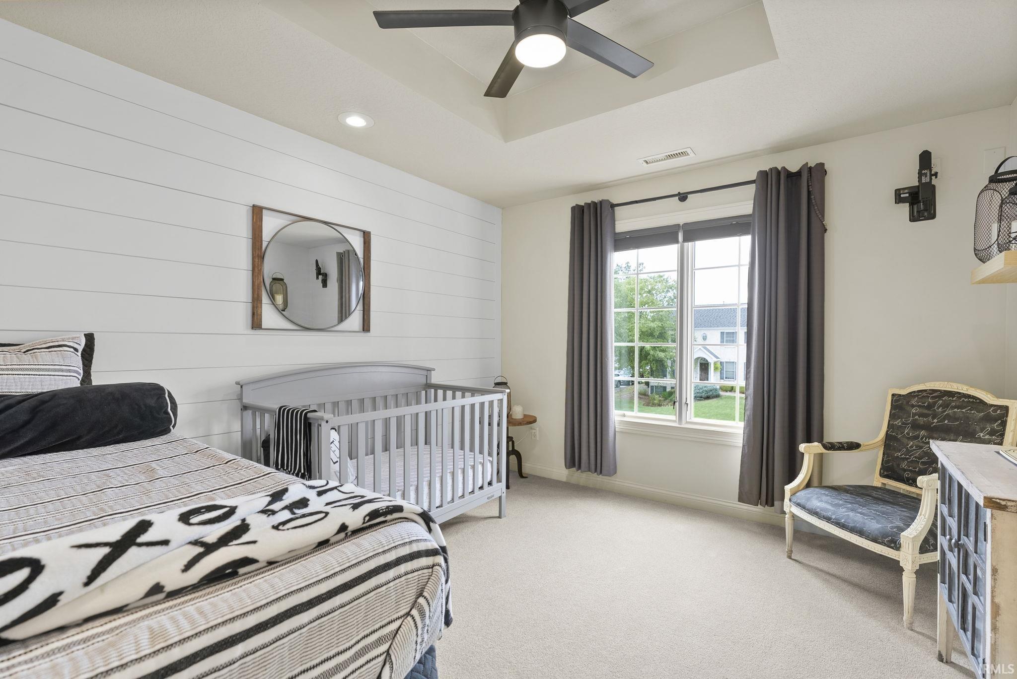 Bedroom featuring a tray ceiling with a ceiling fan, a shiplap accent wall, recessed lighting, and a double window with exterior property visibility