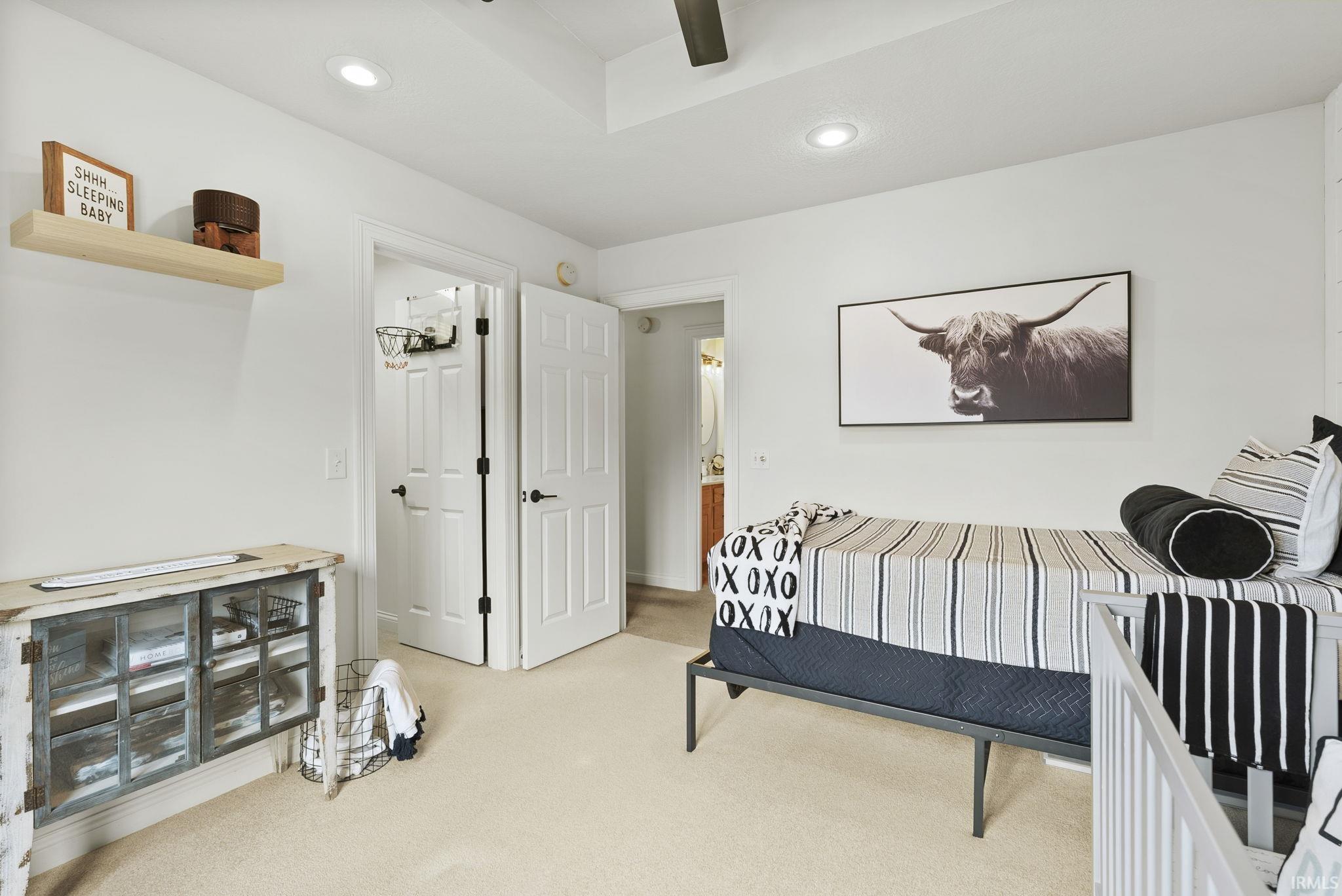 Bright bedroom featuring neutral carpeting, recessed ceiling lighting, and white bi-fold closet doors