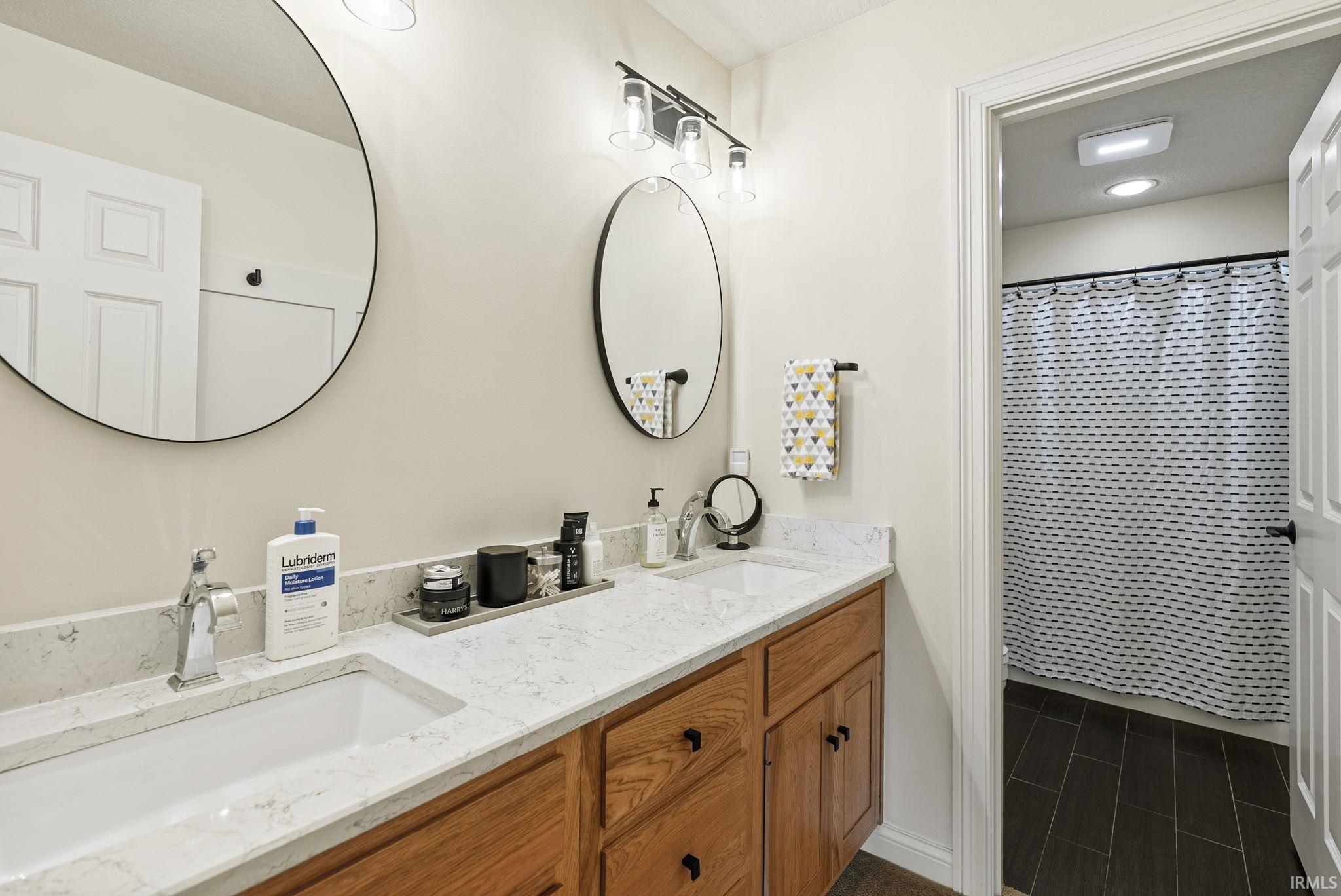 Dual vanity with light wood cabinetry, white countertops, and undermount sinks