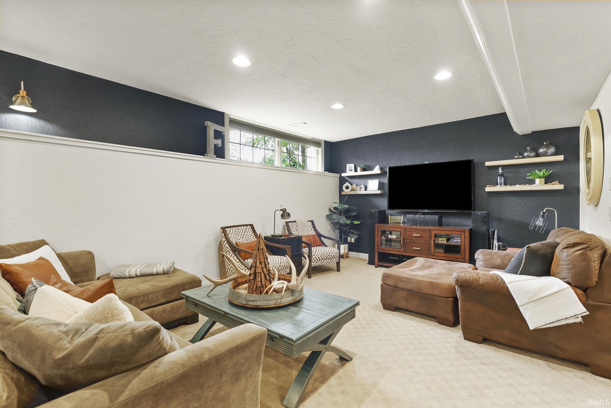 Spacious entertainment area featuring recessed lighting, a modern accent wall, and perimeter windows