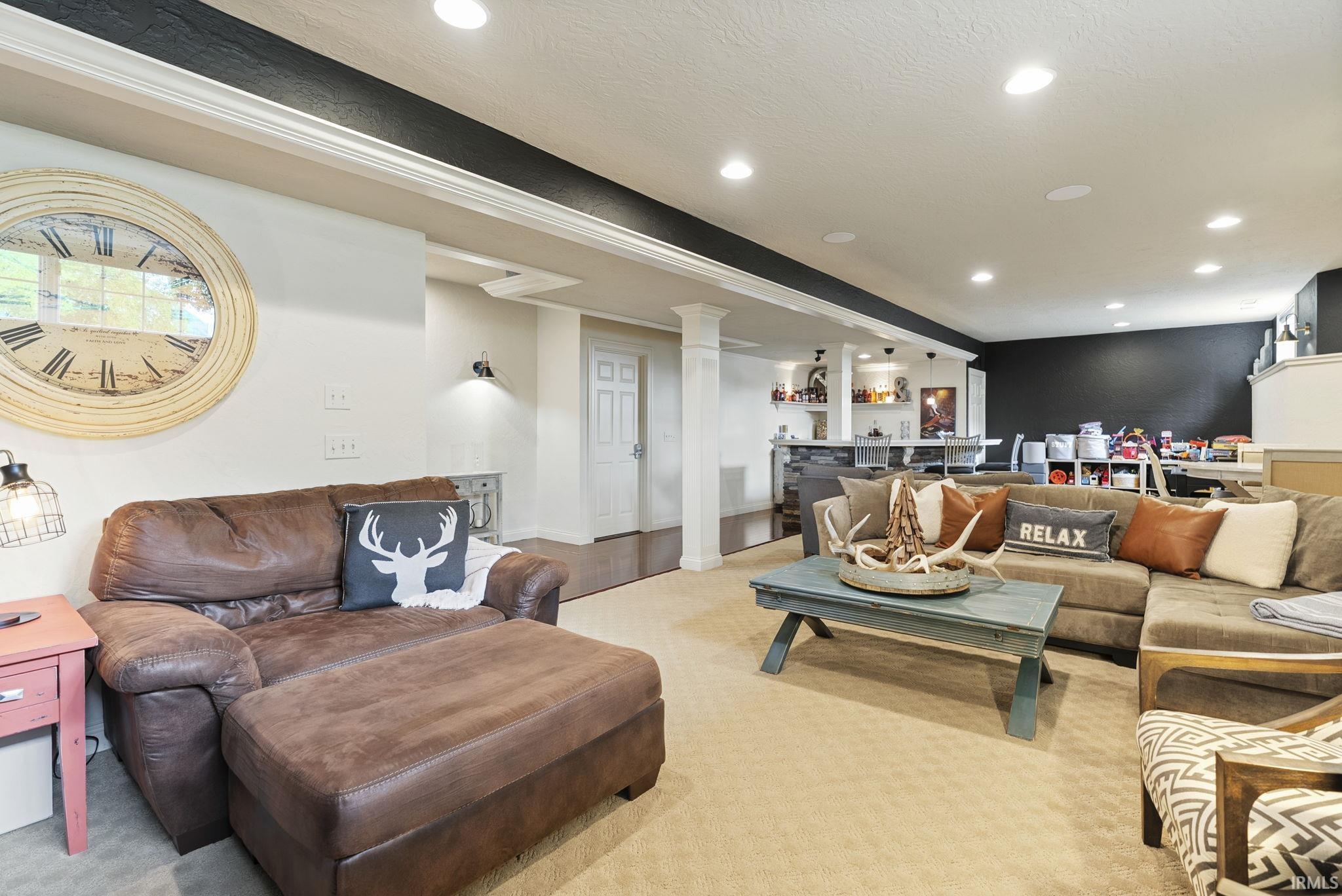 Spacious finished basement featuring a leather sectional seating area, wood-finish flooring, recessed lighting, and a large wall clock