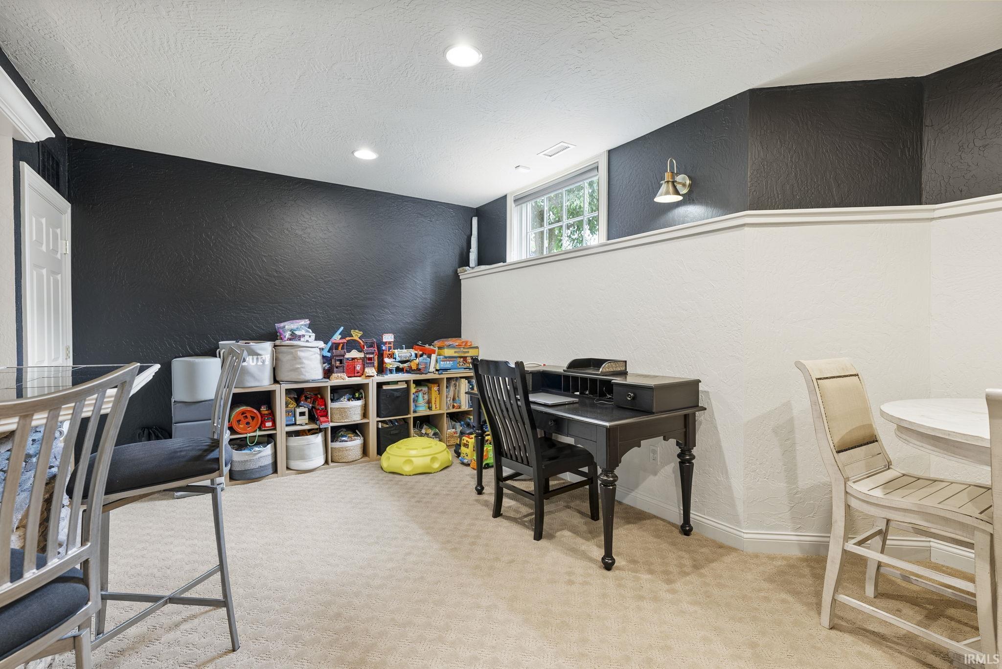 Finished lower level featuring textured dark accent walls and light neutral carpeting