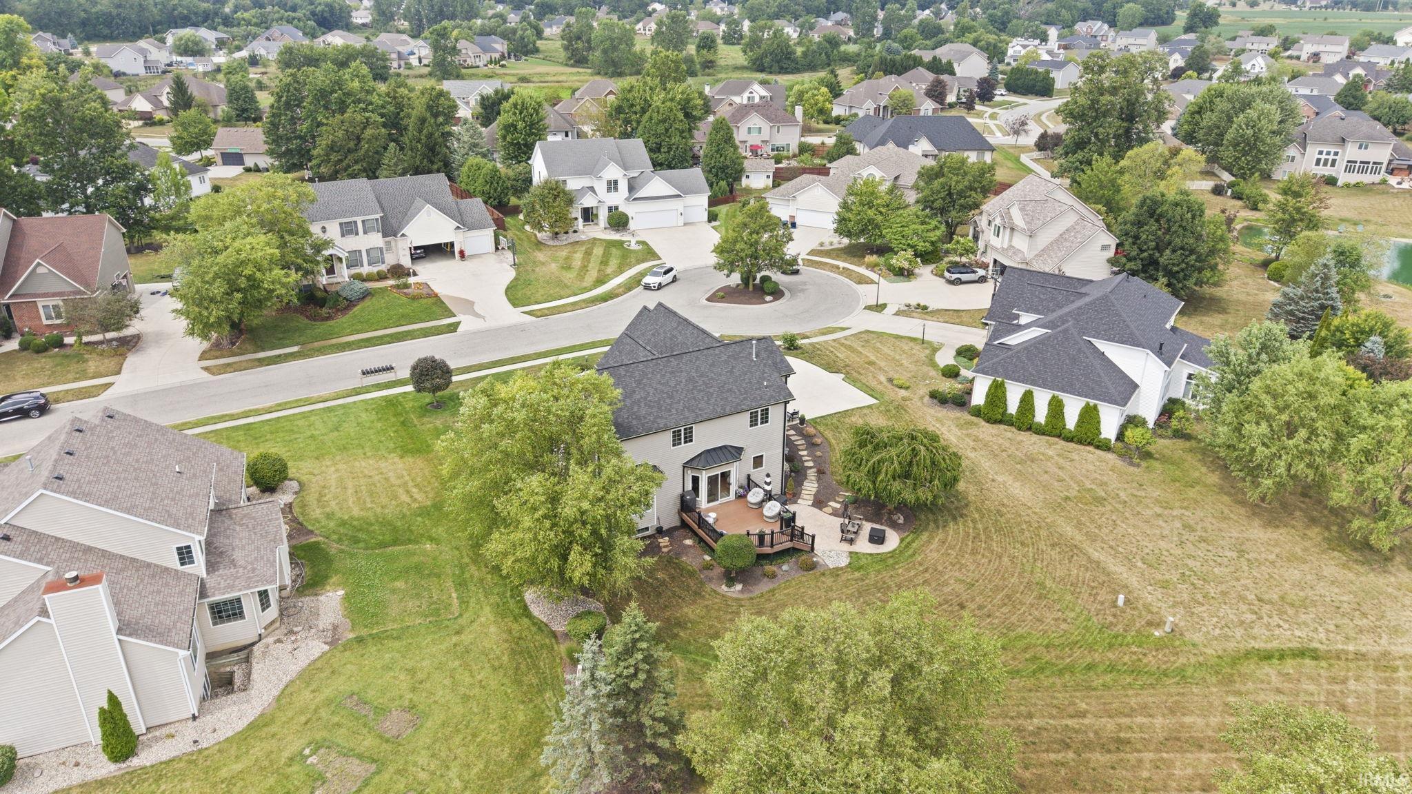 Spacious two-story residence with dark architectural shingle roofing, situated on expansive grounds featuring mature landscaping, manicured lawn areas, and established trees