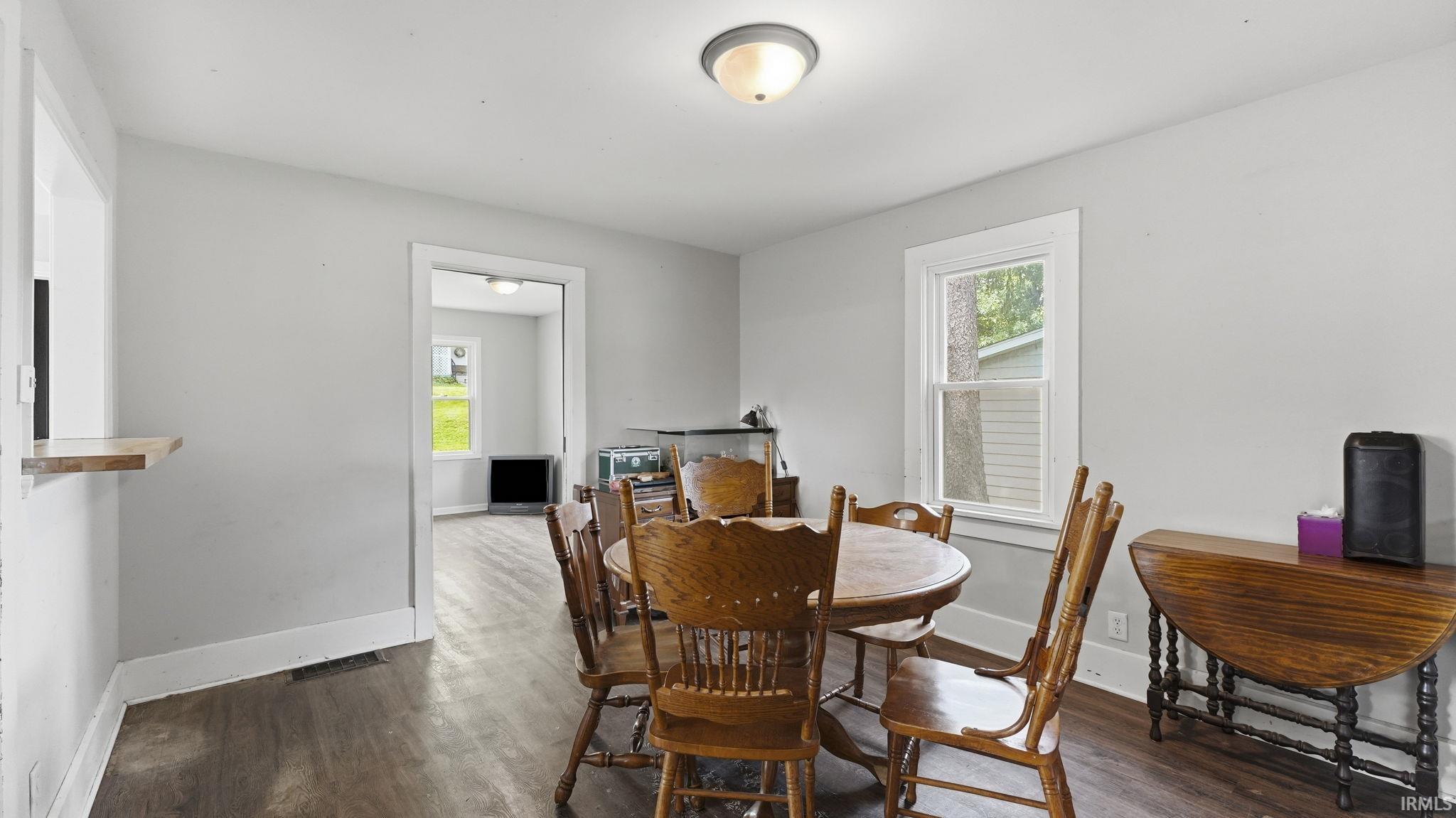 Spacious room featuring wood-finish flooring, light grey wall paint, white trim, and an overhead flush-mount light fixture