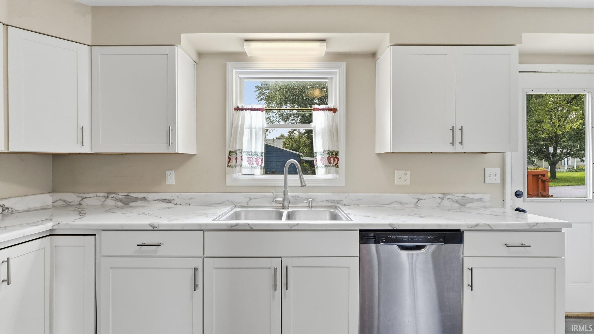 Kitchen featuring white shaker-style cabinetry, a double-basin stainless steel sink, white marble-patterned countertops, and stainless steel dishwasher