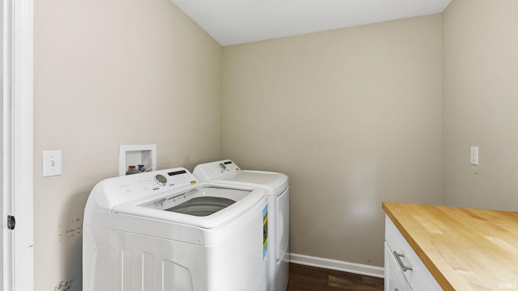 Dedicated utility space featuring wood-finish flooring, light neutral wall paint, and a built-in counter with white cabinetry