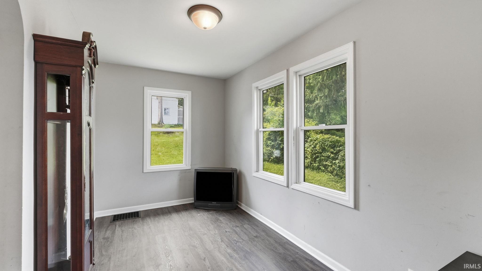 Room featuring wood-finish flooring, light grey walls, white trim, and multiple windows