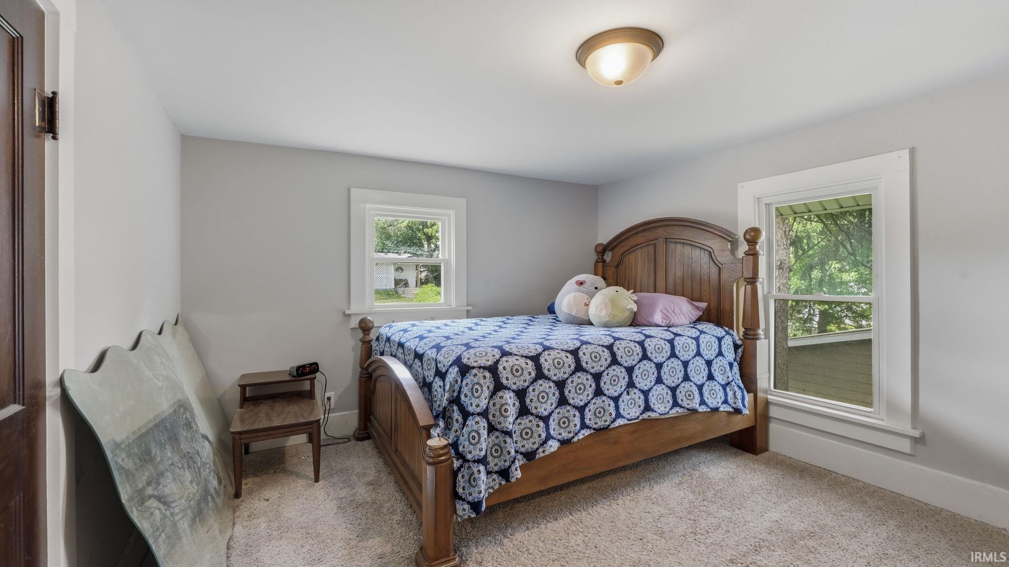 Bedroom featuring light gray wall paint, white trim, two windows, and a flush mount ceiling light