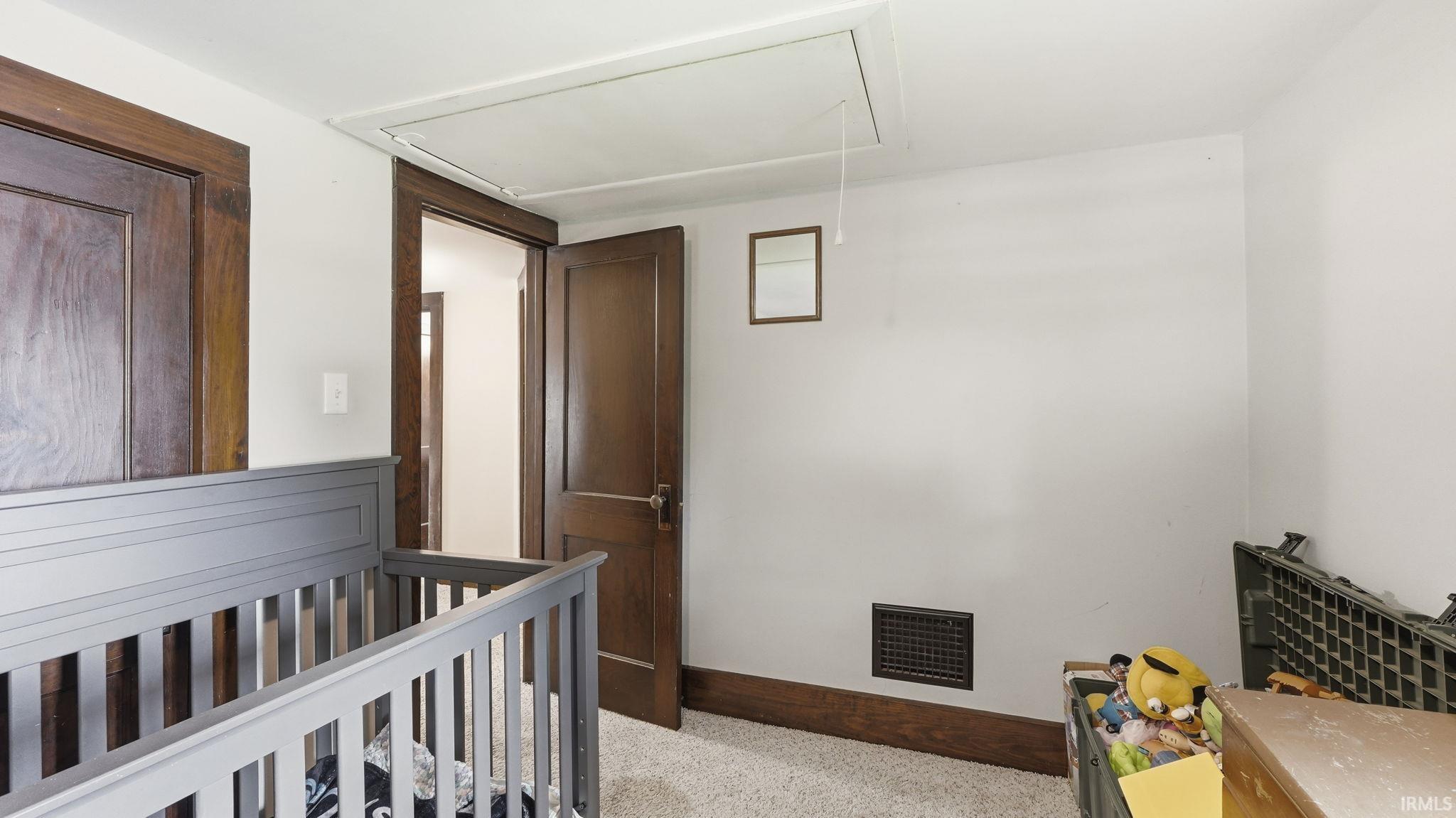 Room featuring light-colored walls, wood-finish doors and trim, and a textured carpeted floor