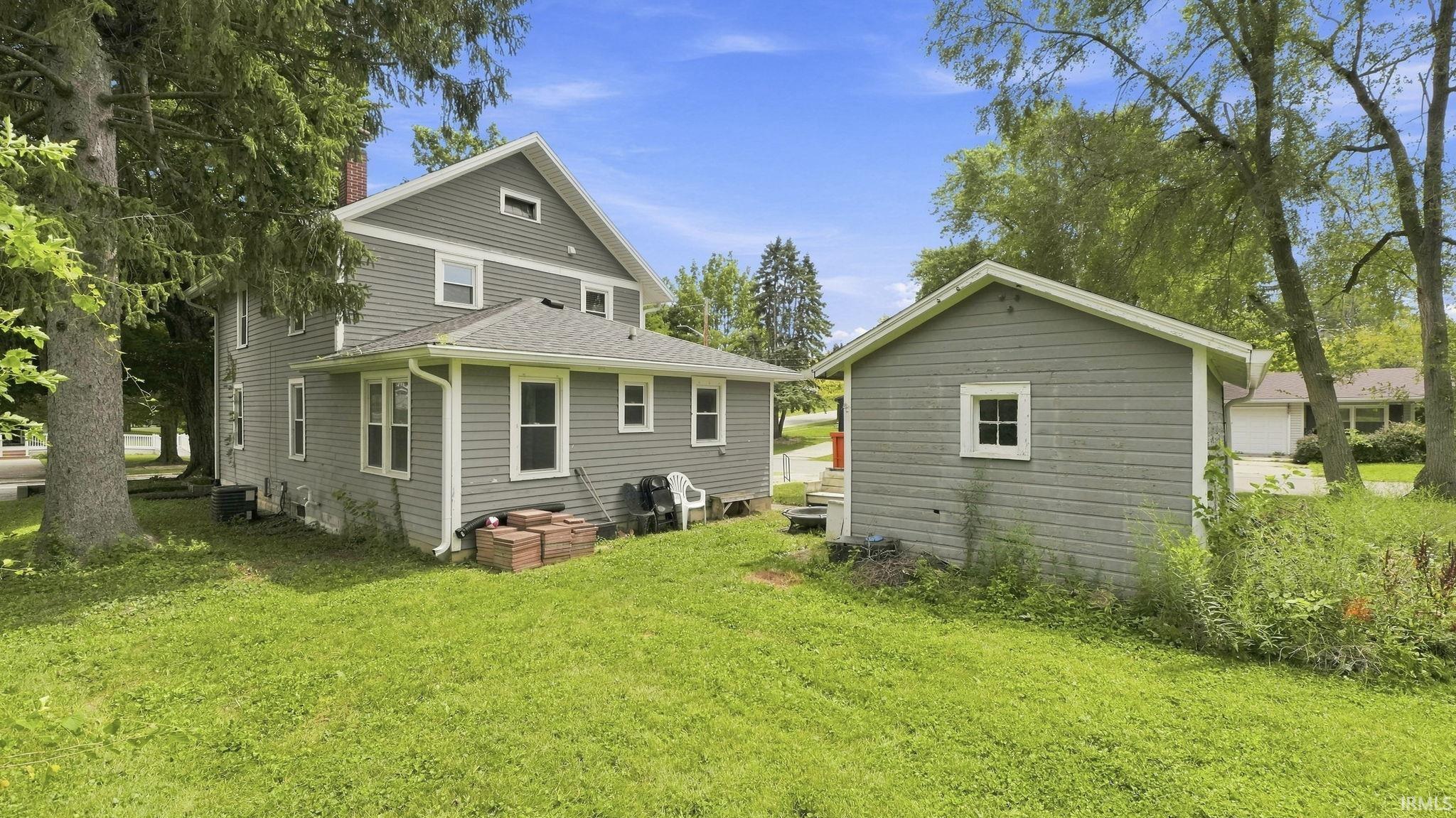 Two-story residence with gray siding and white trim, featuring a side-gabled roof and an exterior chimney
