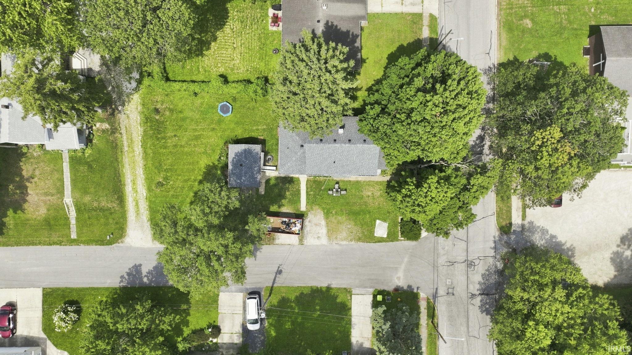 Aerial perspective highlighting a corner property with mature trees and green lawns