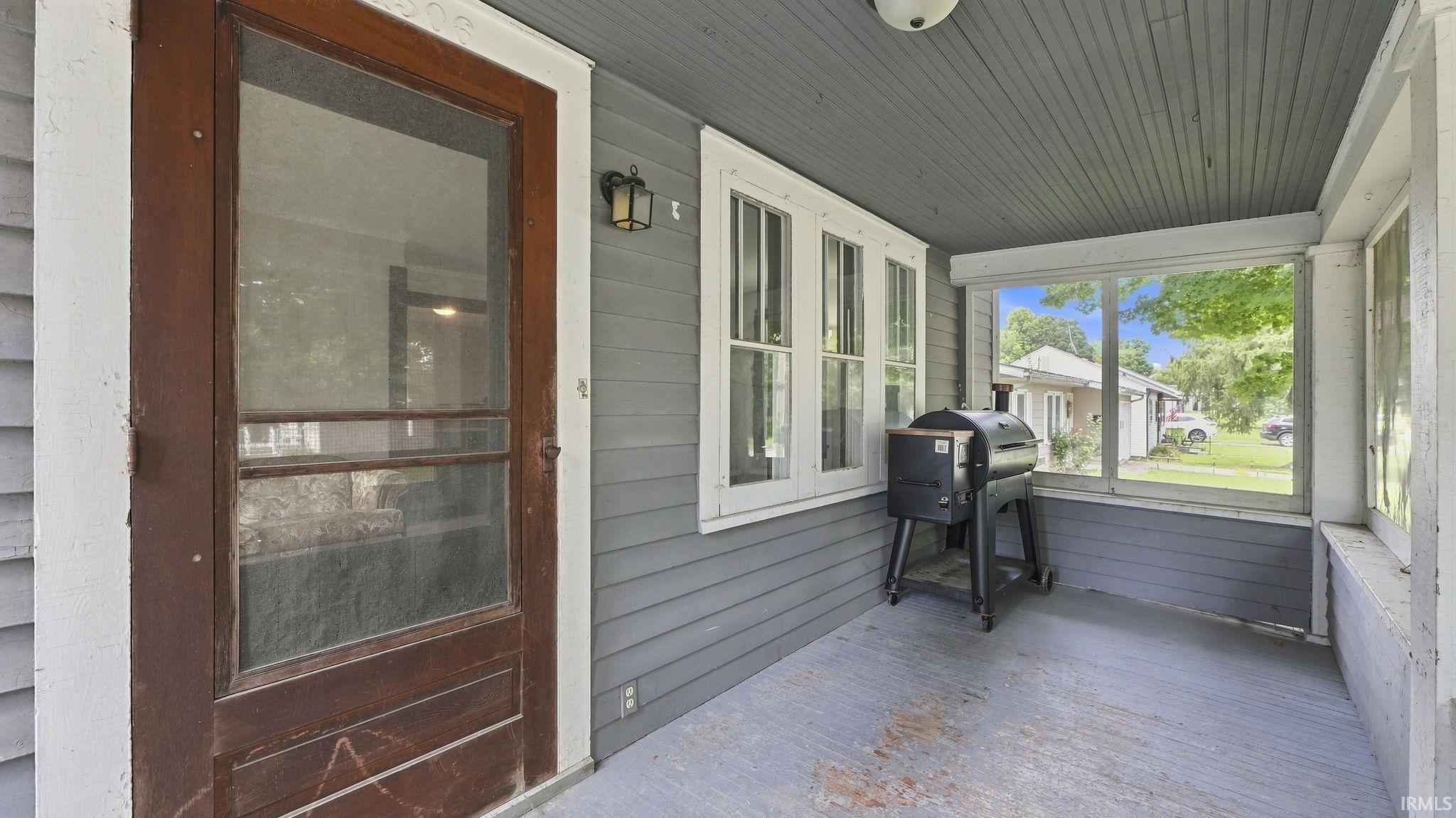 Screened porch featuring gray siding, a wood-paneled ceiling, and multiple windows
