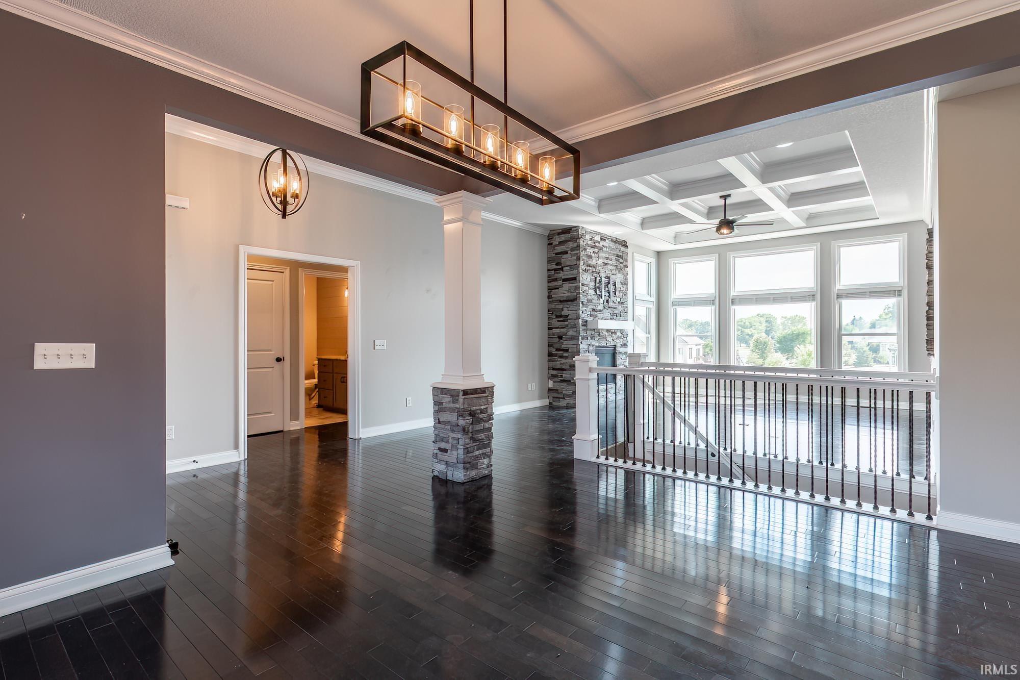 Spacious interior featuring dark wood-finish flooring, a coffered ceiling, and a prominent stone fireplace