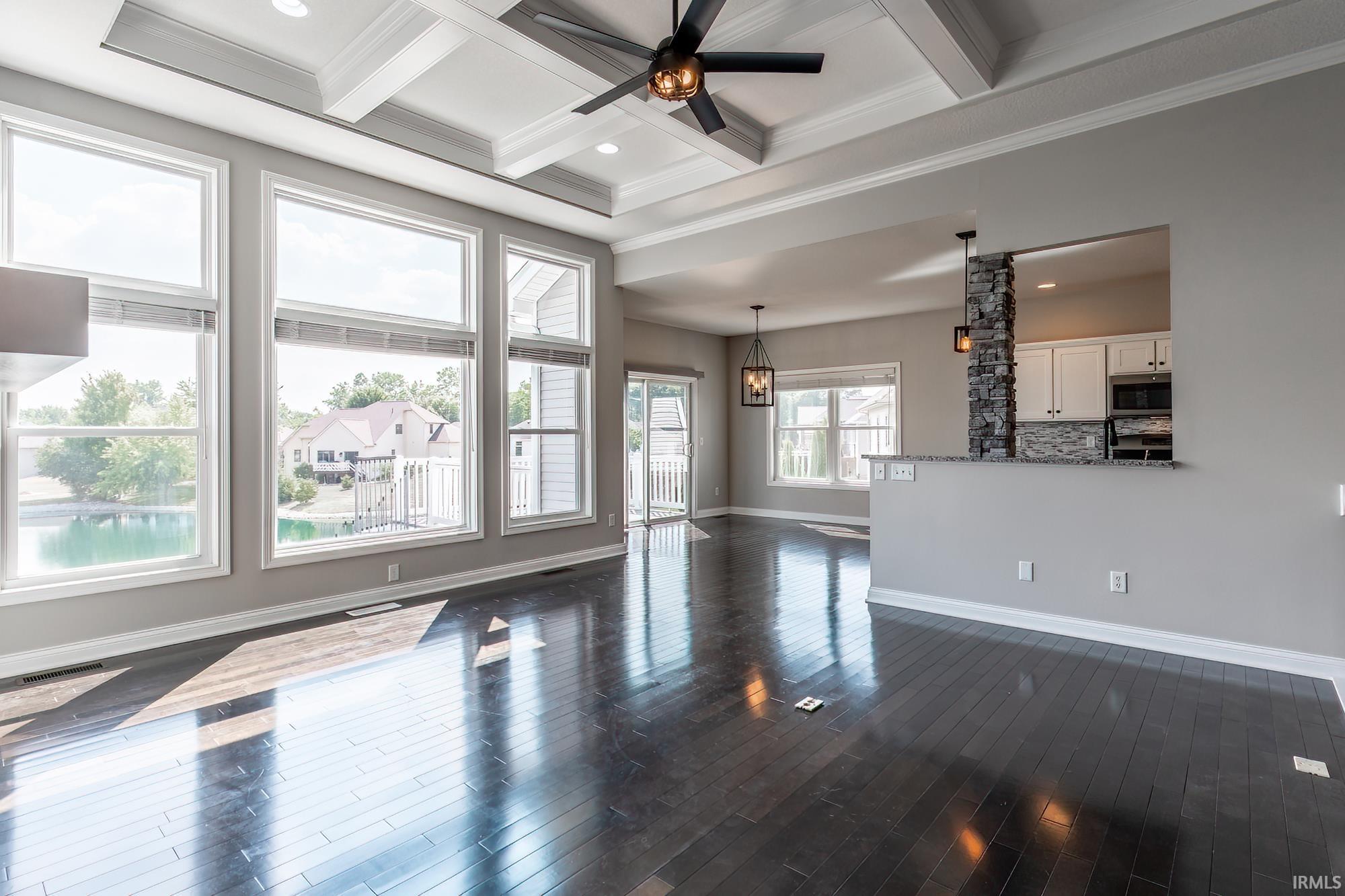Spacious living area featuring coffered ceilings and dark wood-finish flooring