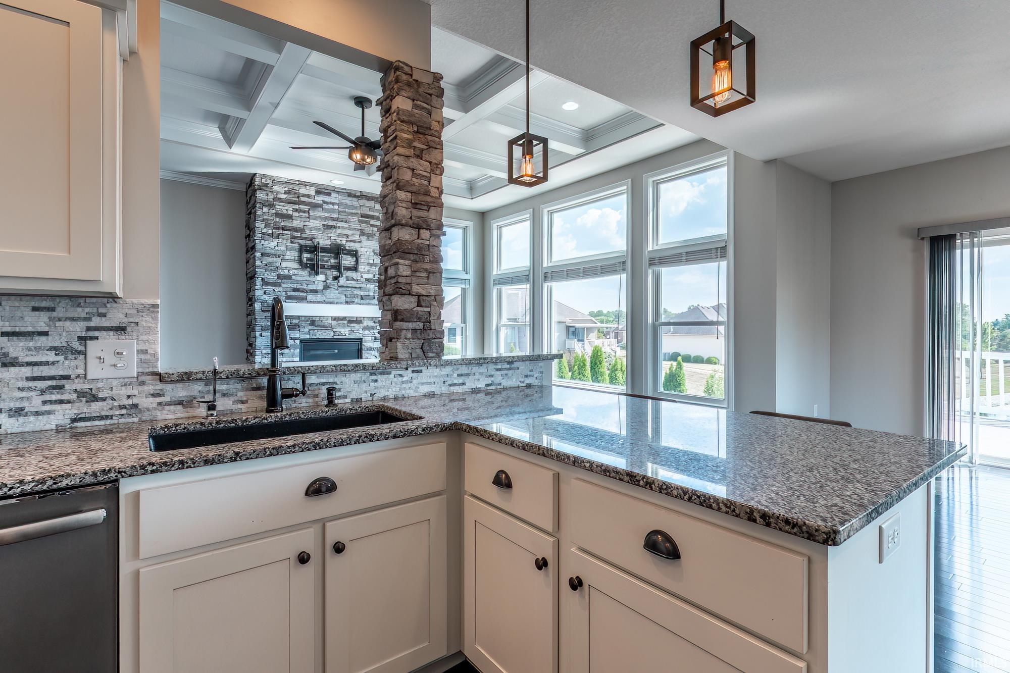 Kitchen featuring a black sink, integrated dishwasher, and granite countertops
