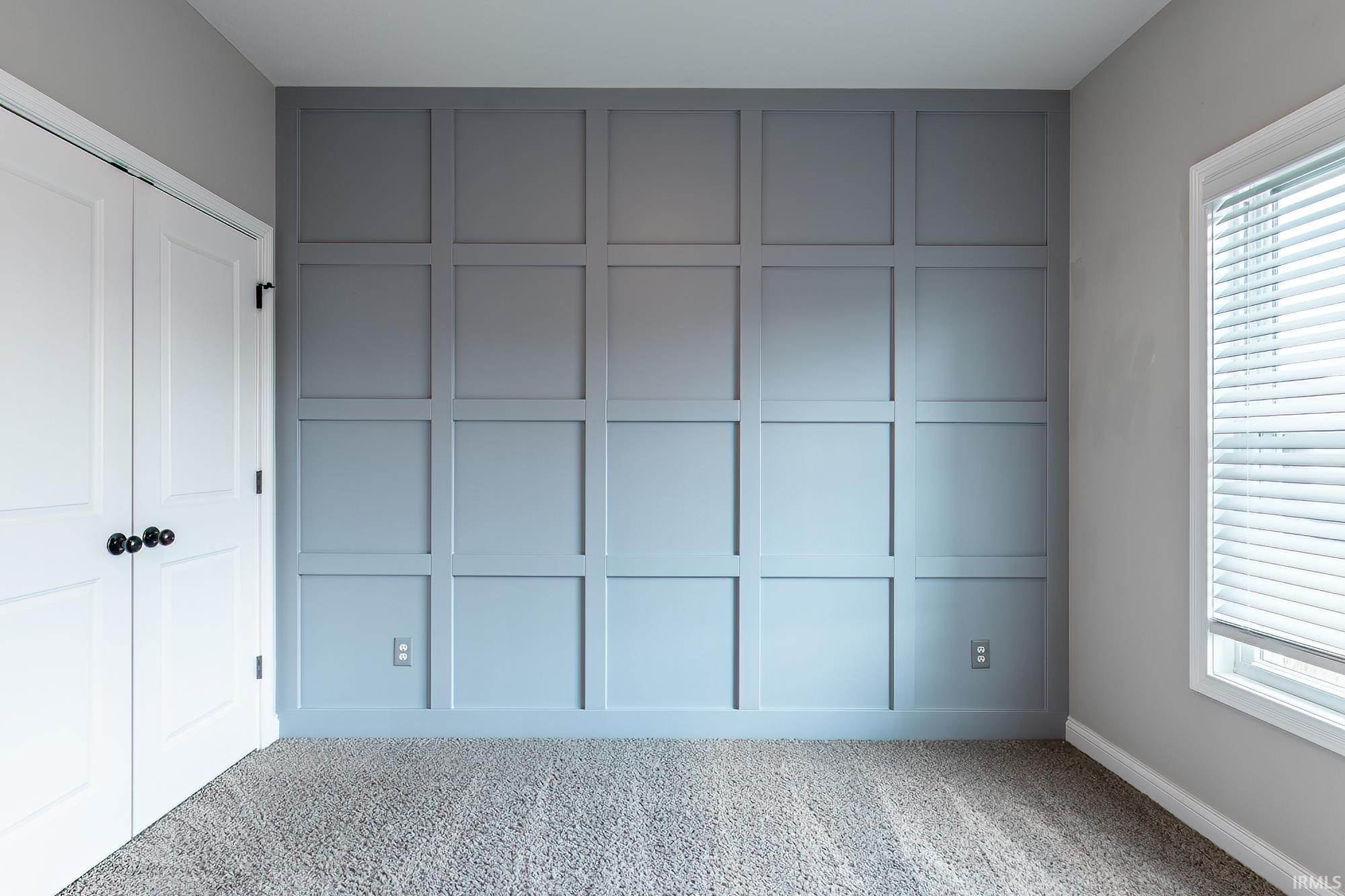 Accent wall featuring light grey wainscoting and baseboard trim