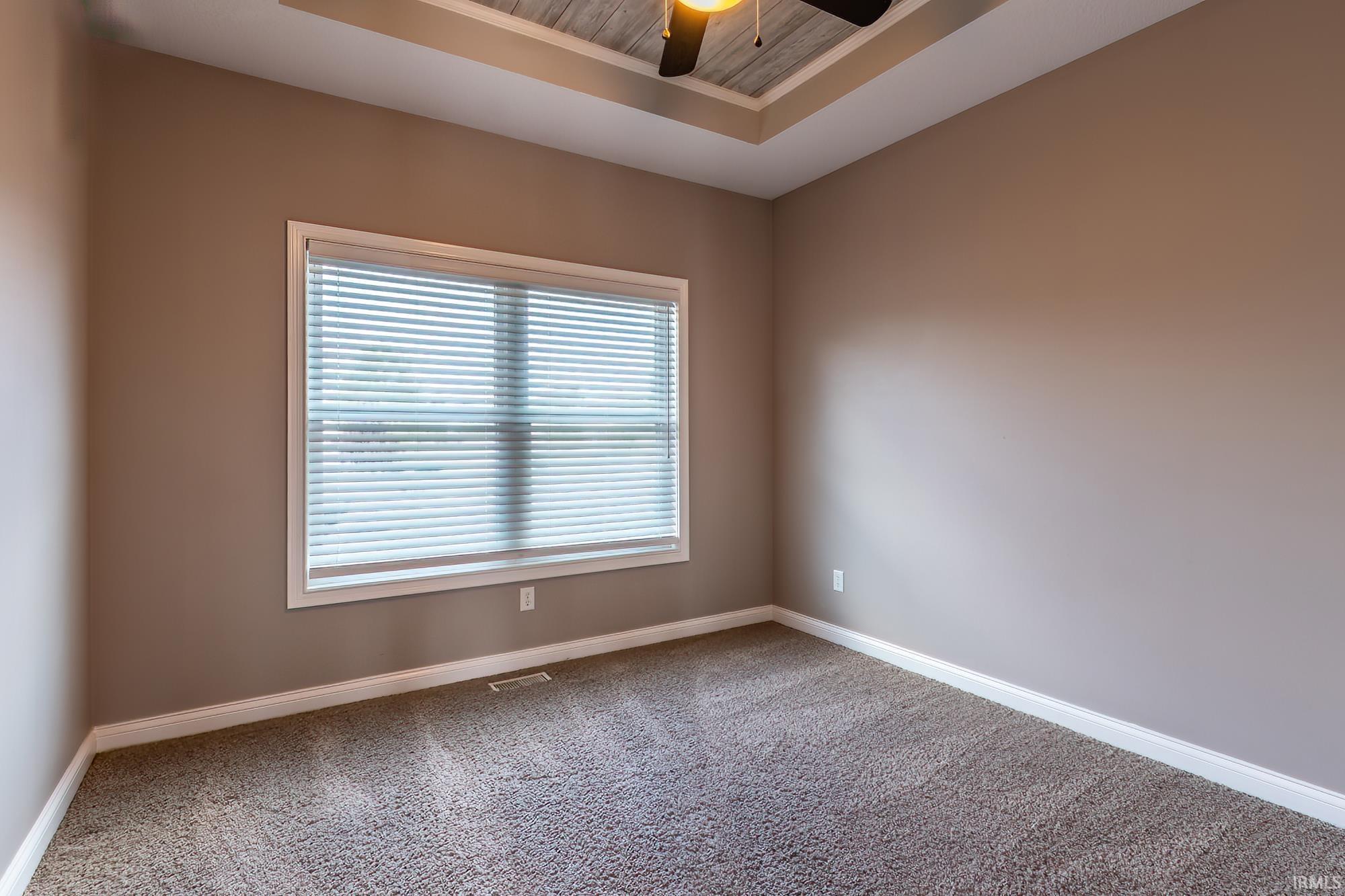 Recessed tray ceiling with wood-finish accent paneling and a ceiling fan with light fixture