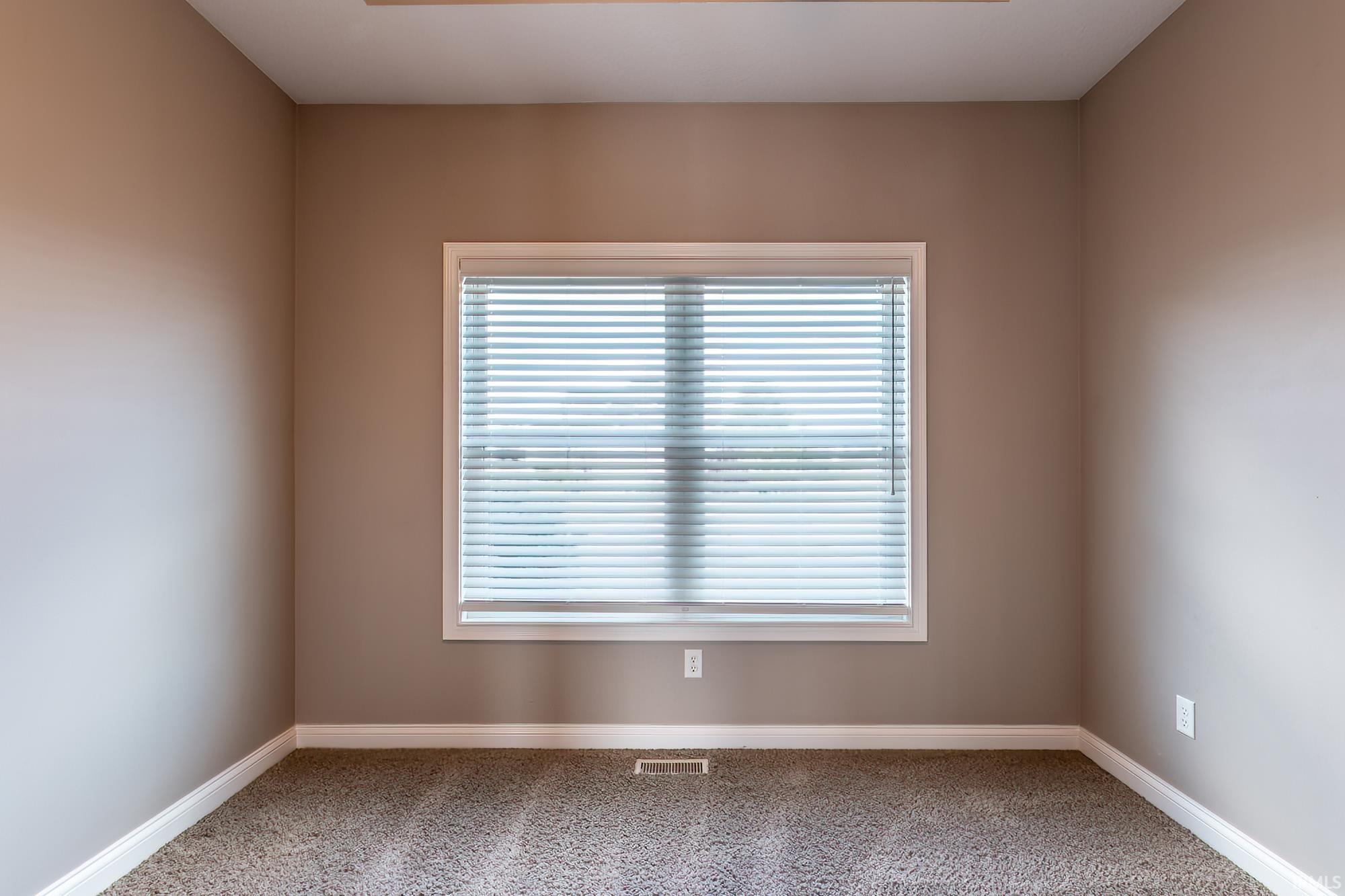 Neutral-toned walls complement the window with white trim and horizontal blinds