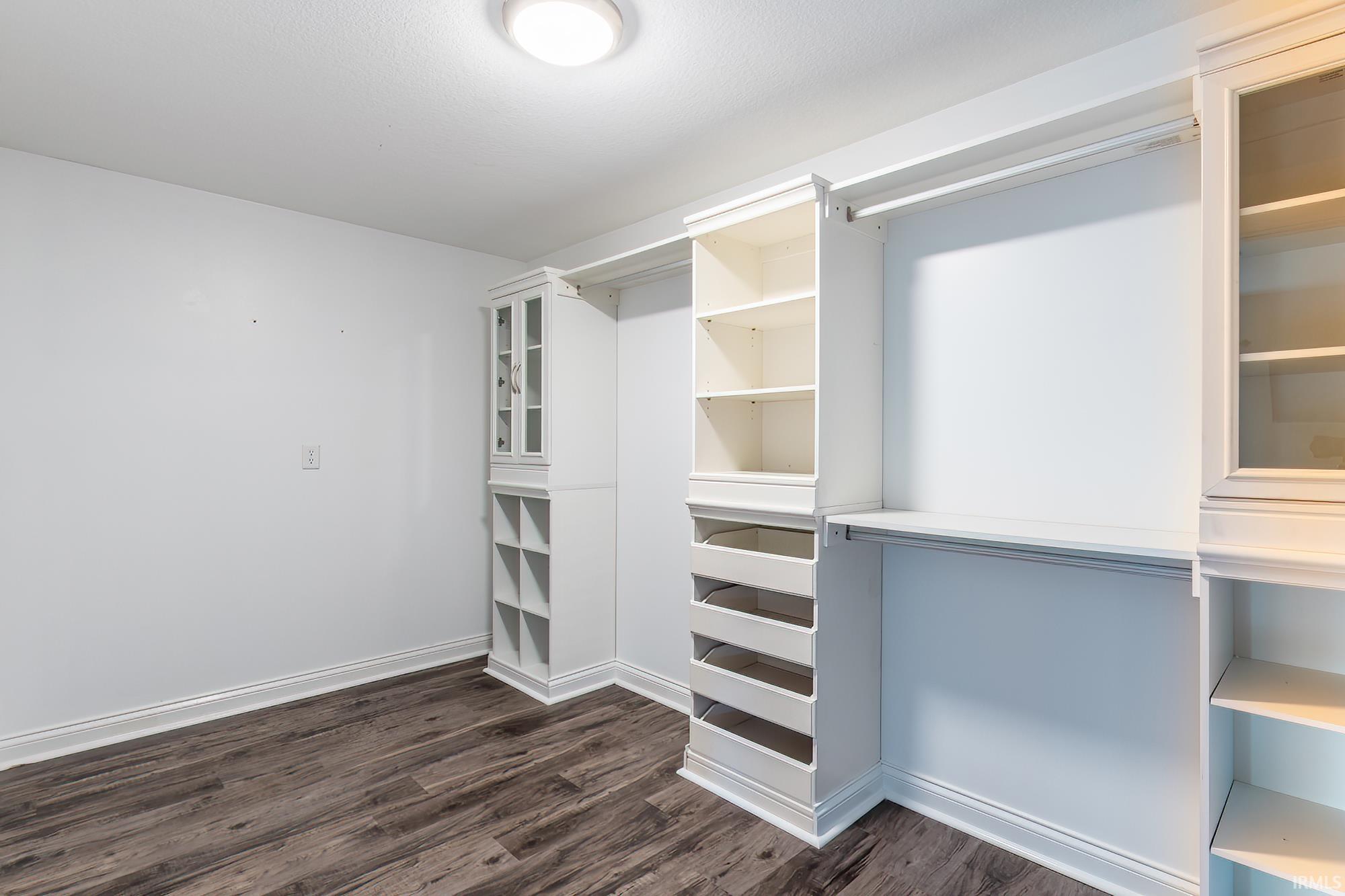 Custom closet system featuring built-in shelving, glass-front cabinetry, drawers, and hanging rods
