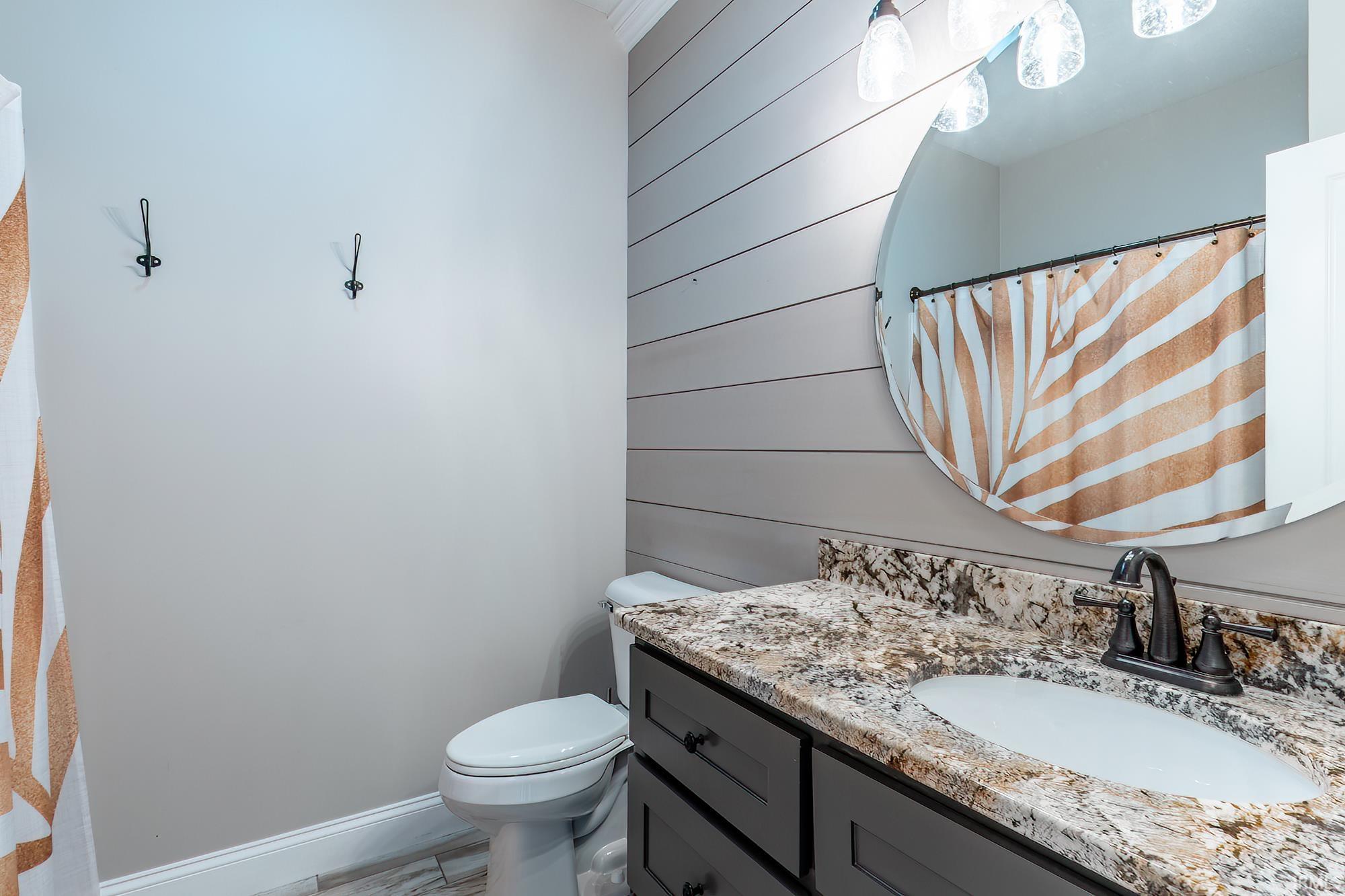 Bathroom featuring a dark wood-finish vanity with a granite countertop and an undermount sink