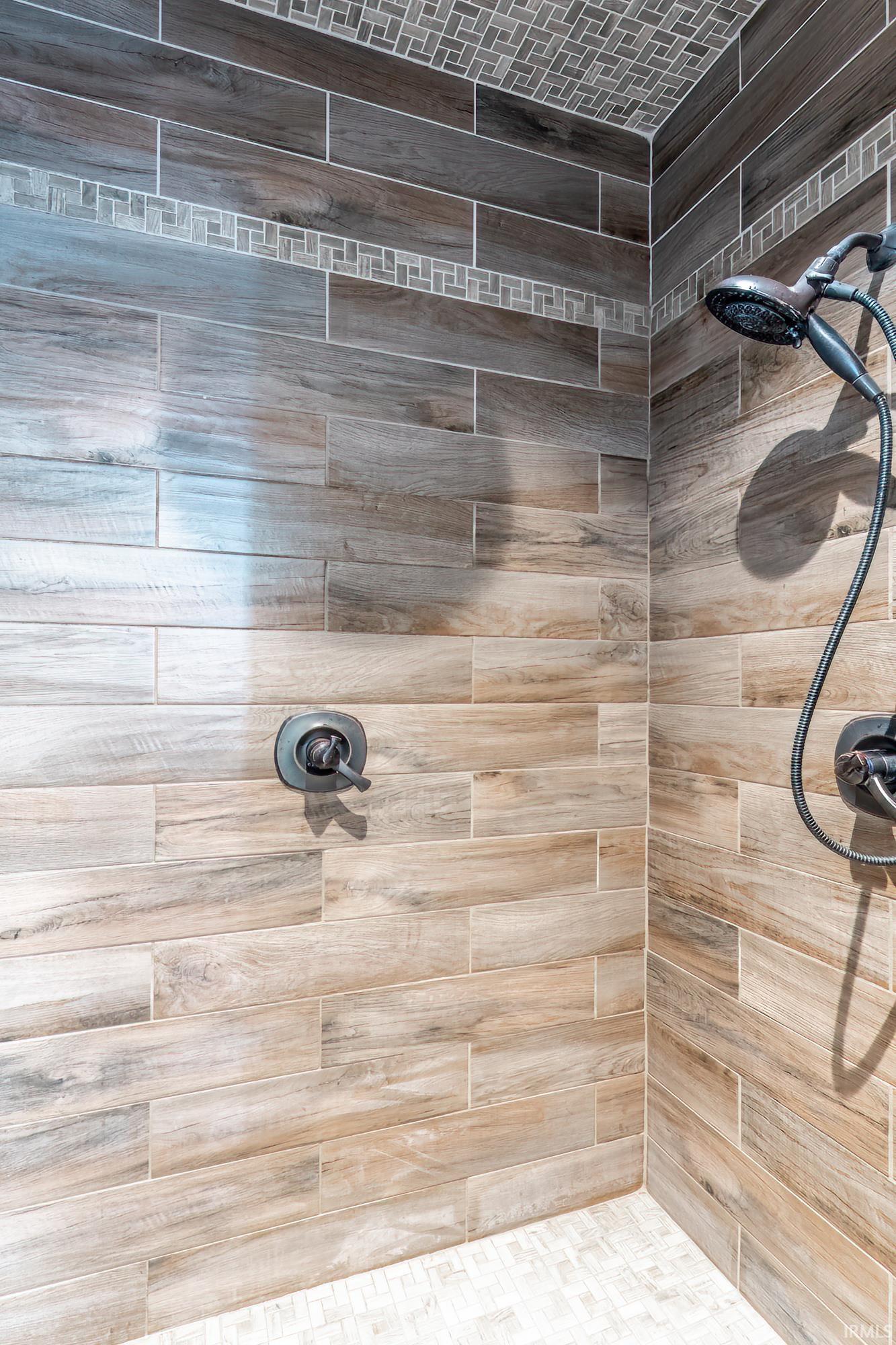 Walk-in shower with wood-finish tile walls, a decorative mosaic tile band, and a mosaic tile ceiling