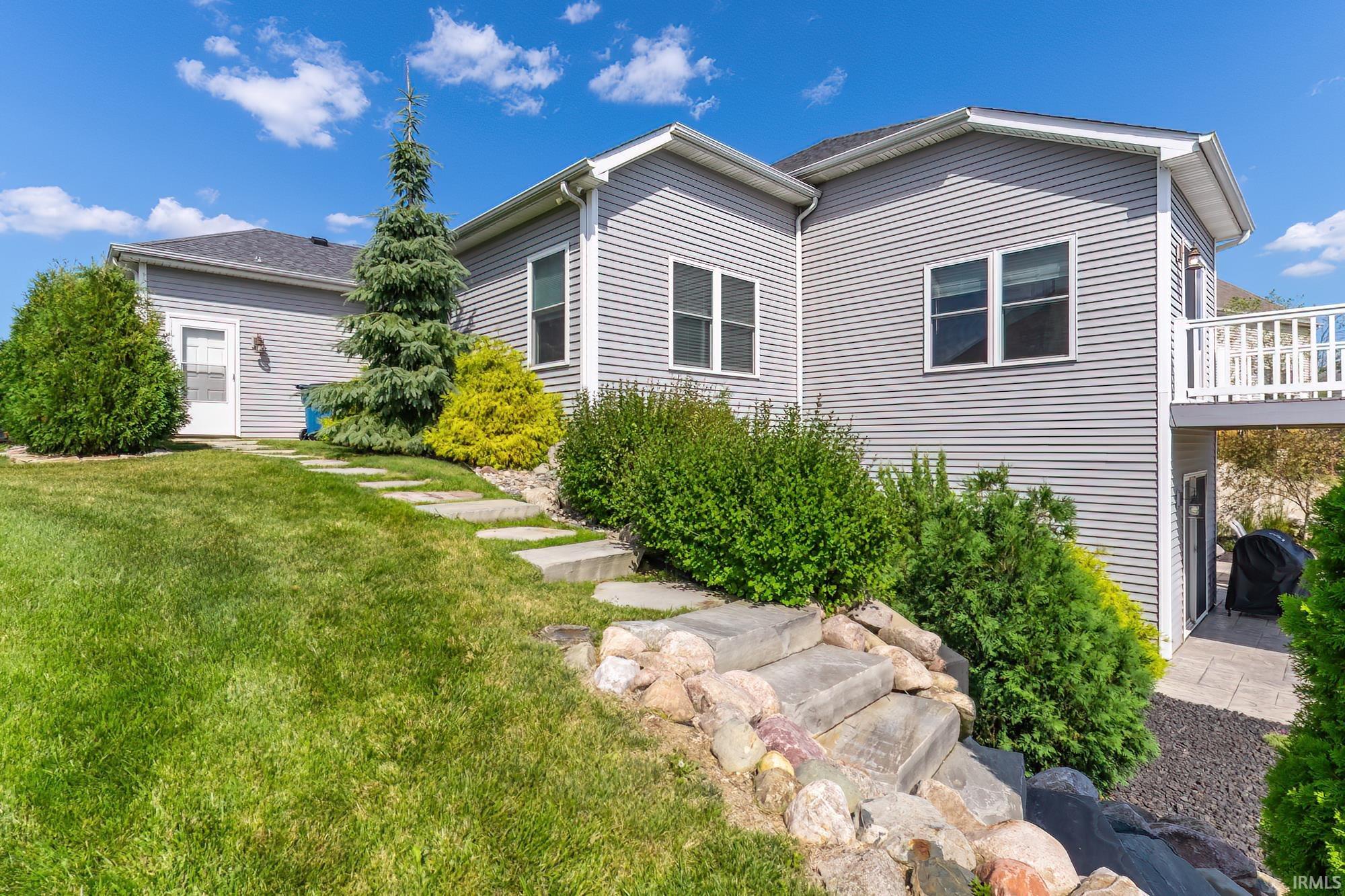 Exterior featuring gray horizontal siding, a terraced stone staircase, and a ground-level patio
