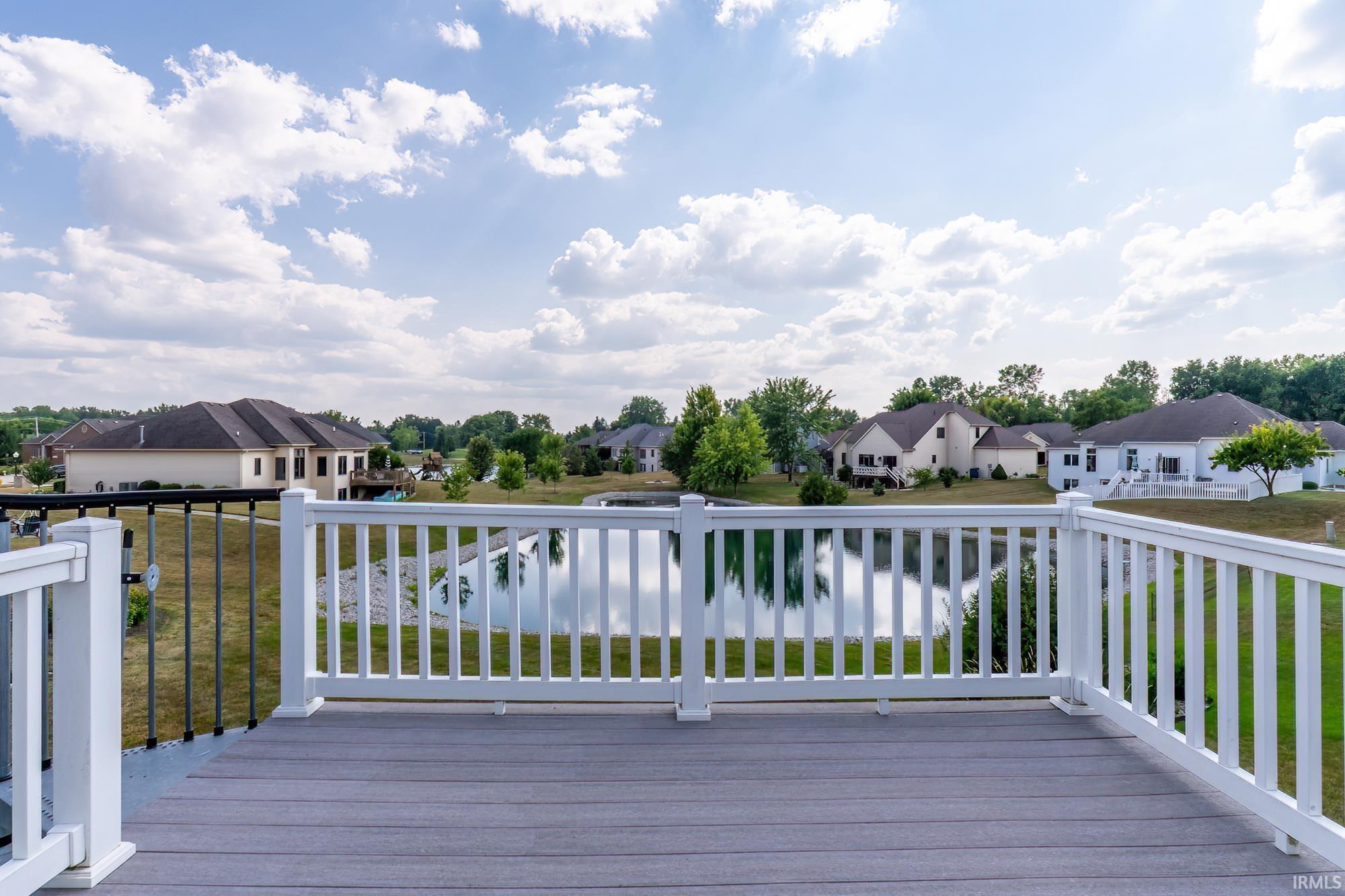Elevated composite decking with white railing overlooking a pond and distant properties