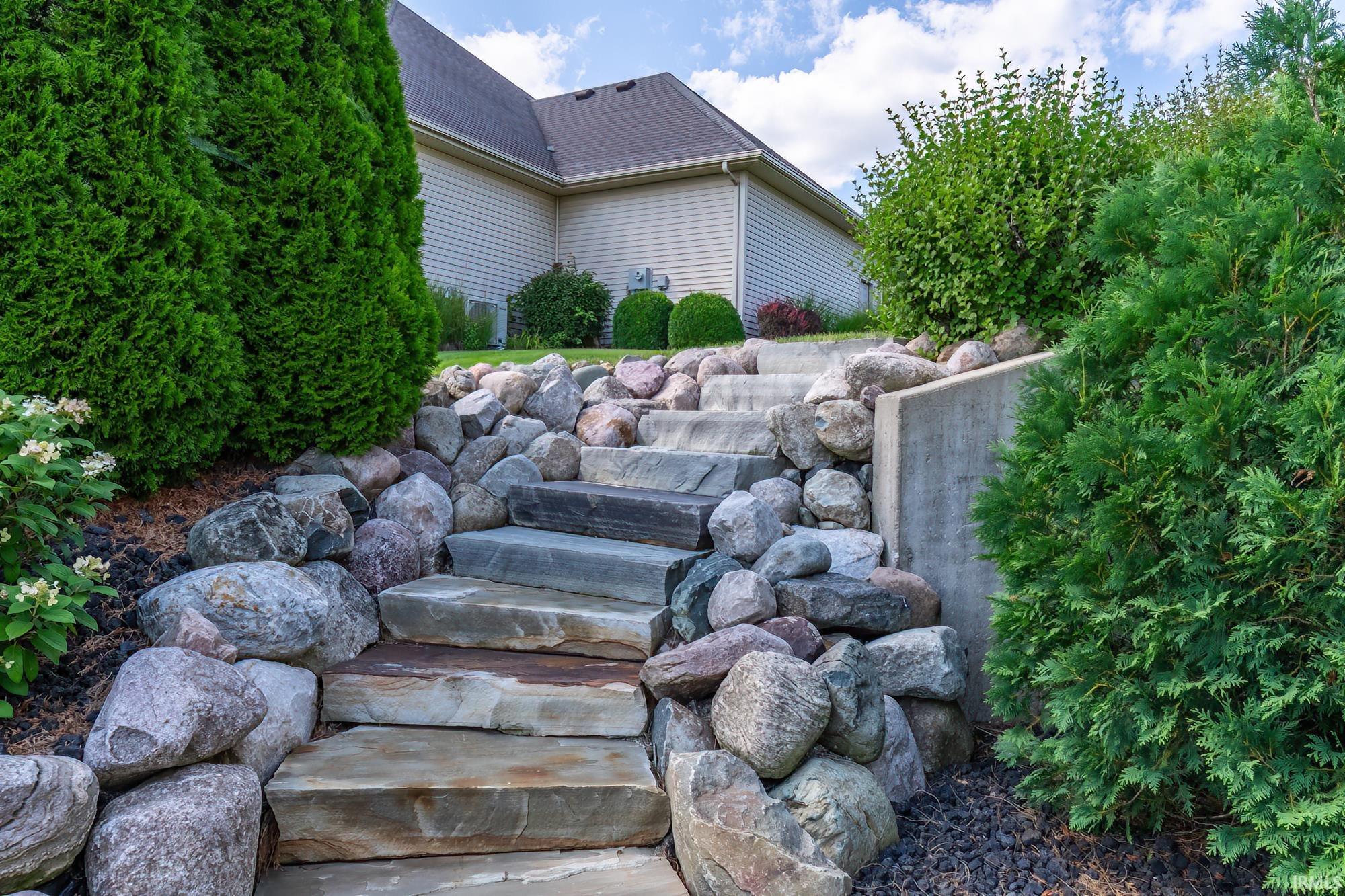 Striking natural stone staircase and retaining walls create dramatic architectural interest in this expertly landscaped outdoor space