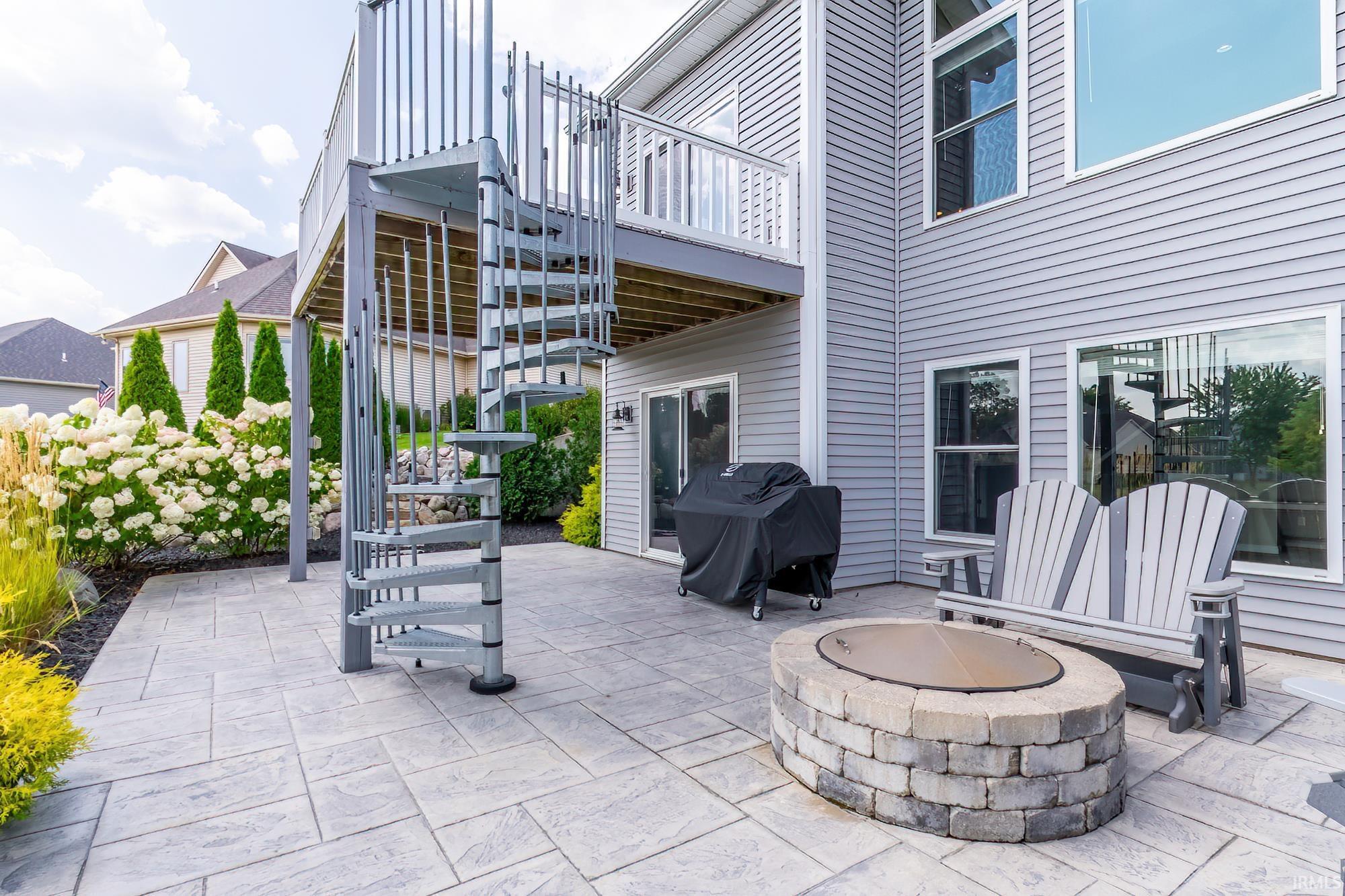 Expansive stamped concrete patio featuring a stone fire pit