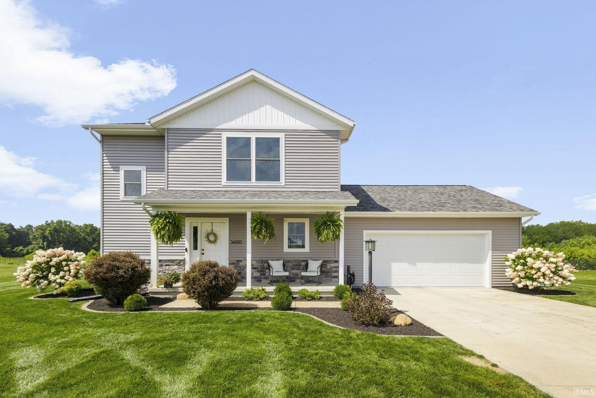 Two-story home with a light gray siding facade and stone accent detailing