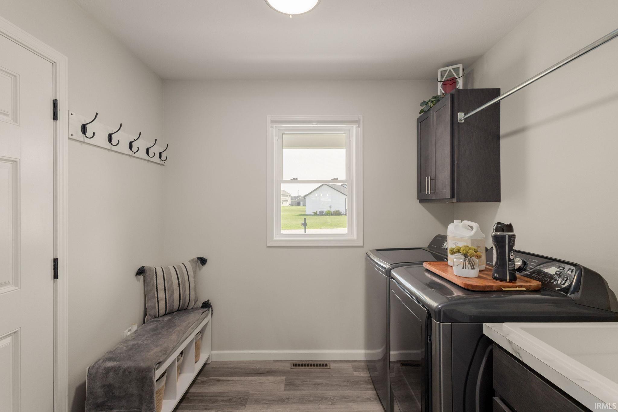 Dedicated laundry area featuring a built-in hanging rod, wall-mounted cabinetry, and a window