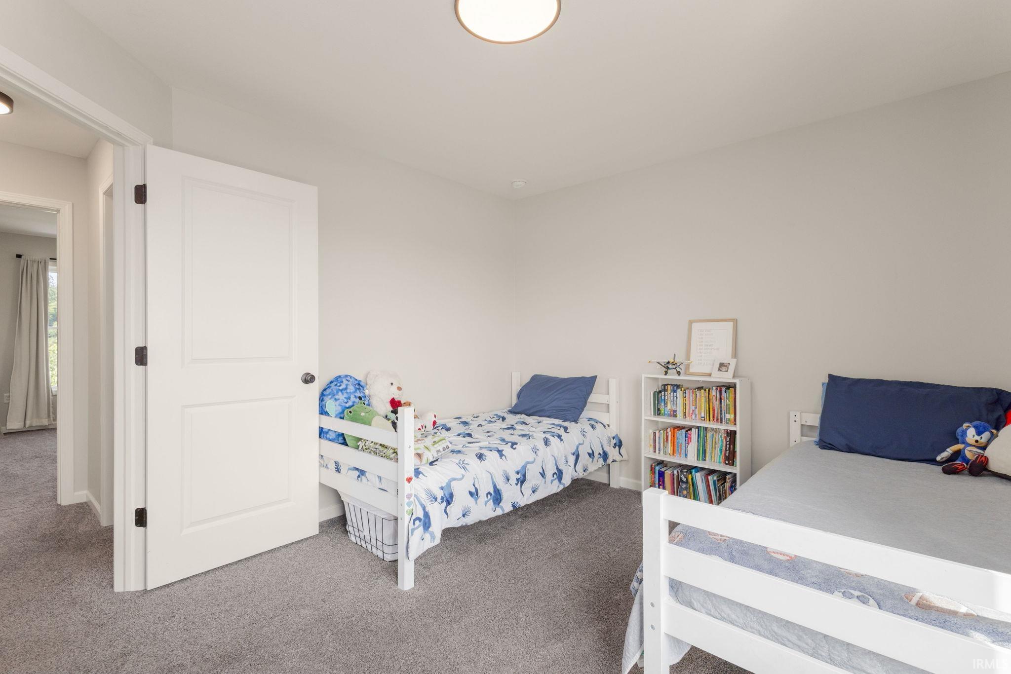 Bright interior room featuring a neutral color palette, plush grey carpeting, white interior doors with dark hardware, and a semi-flush mount ceiling light fixture