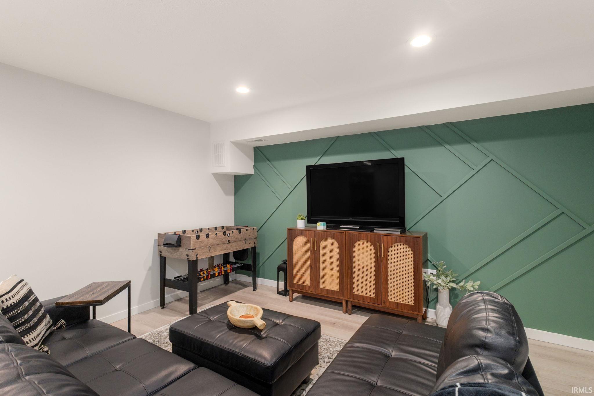 Entertainment space featuring light wood-finish flooring and recessed ceiling lighting
