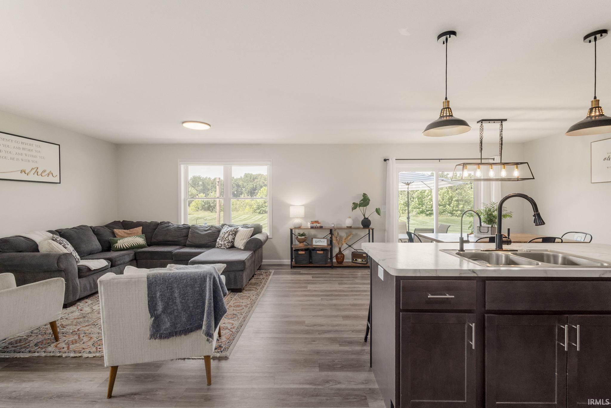 Kitchen island with a double basin sink, dark wood-finish cabinetry, and light-toned countertops