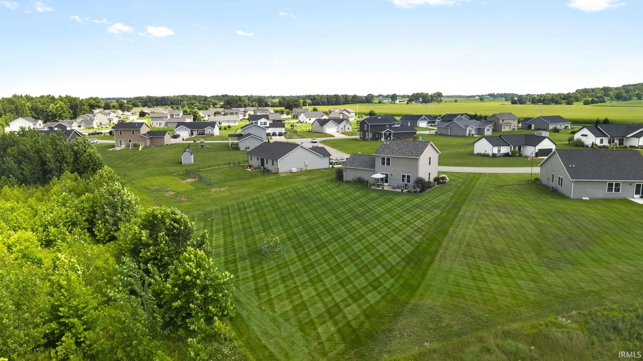 Expansive green spaces define this neighborhood setting, featuring multiple residential structures with dark shingle roofing