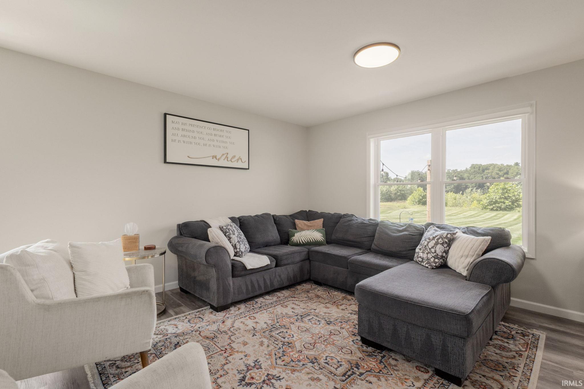 Living area with light gray walls, wood-finish flooring, and a large window