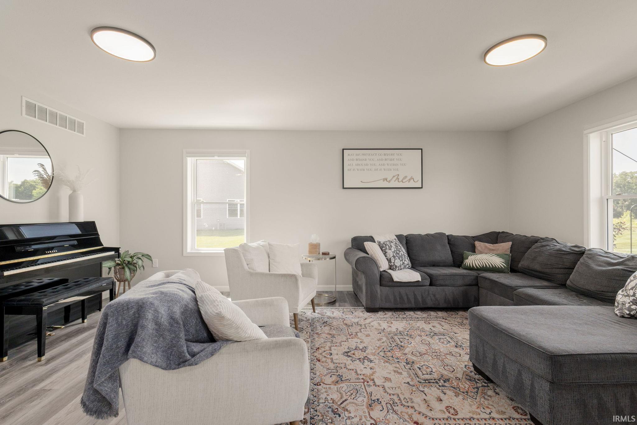 Spacious living area featuring light gray wall paint and wood-finish flooring