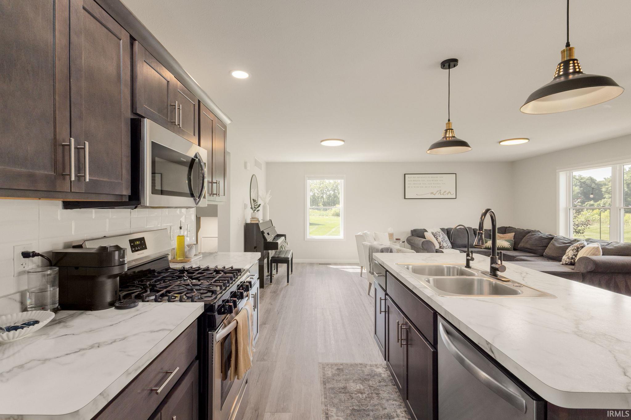Kitchen with dark wood-finish cabinetry, stainless steel appliances, and light-colored countertops