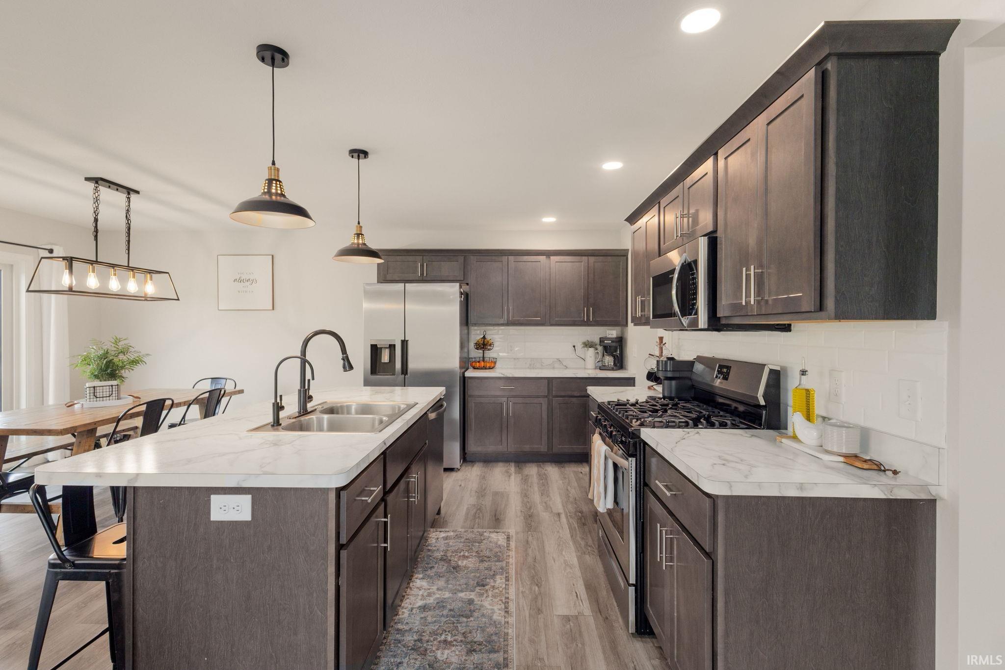 Kitchen featuring dark wood-finish cabinetry, light marble-patterned countertops, and stainless steel appliances