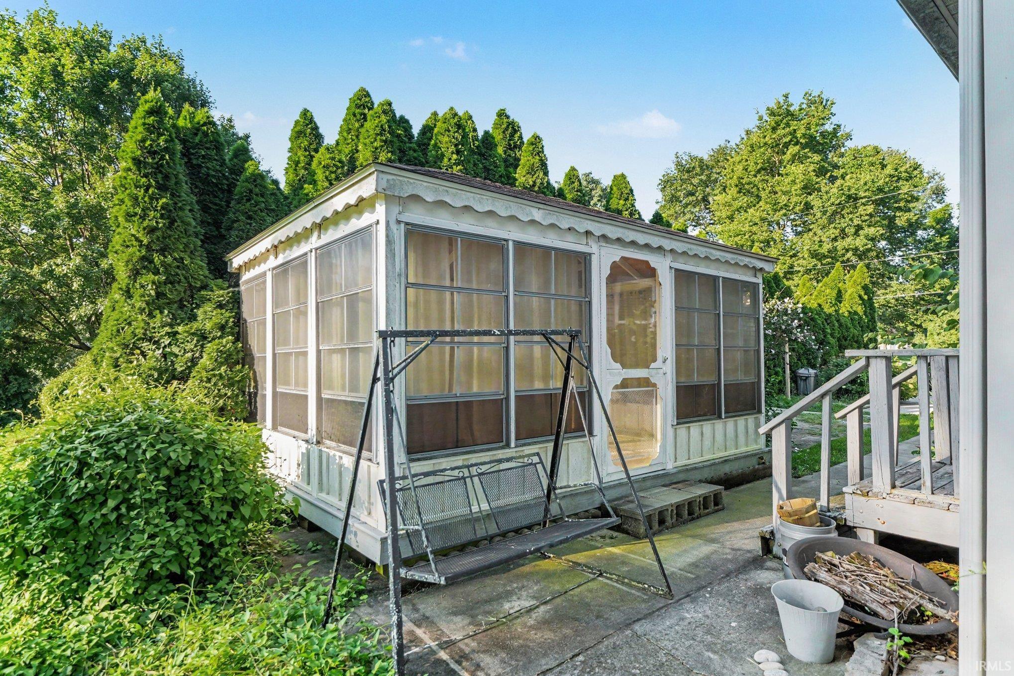 Enclosed porch structure featuring white exterior siding and decorative trim details