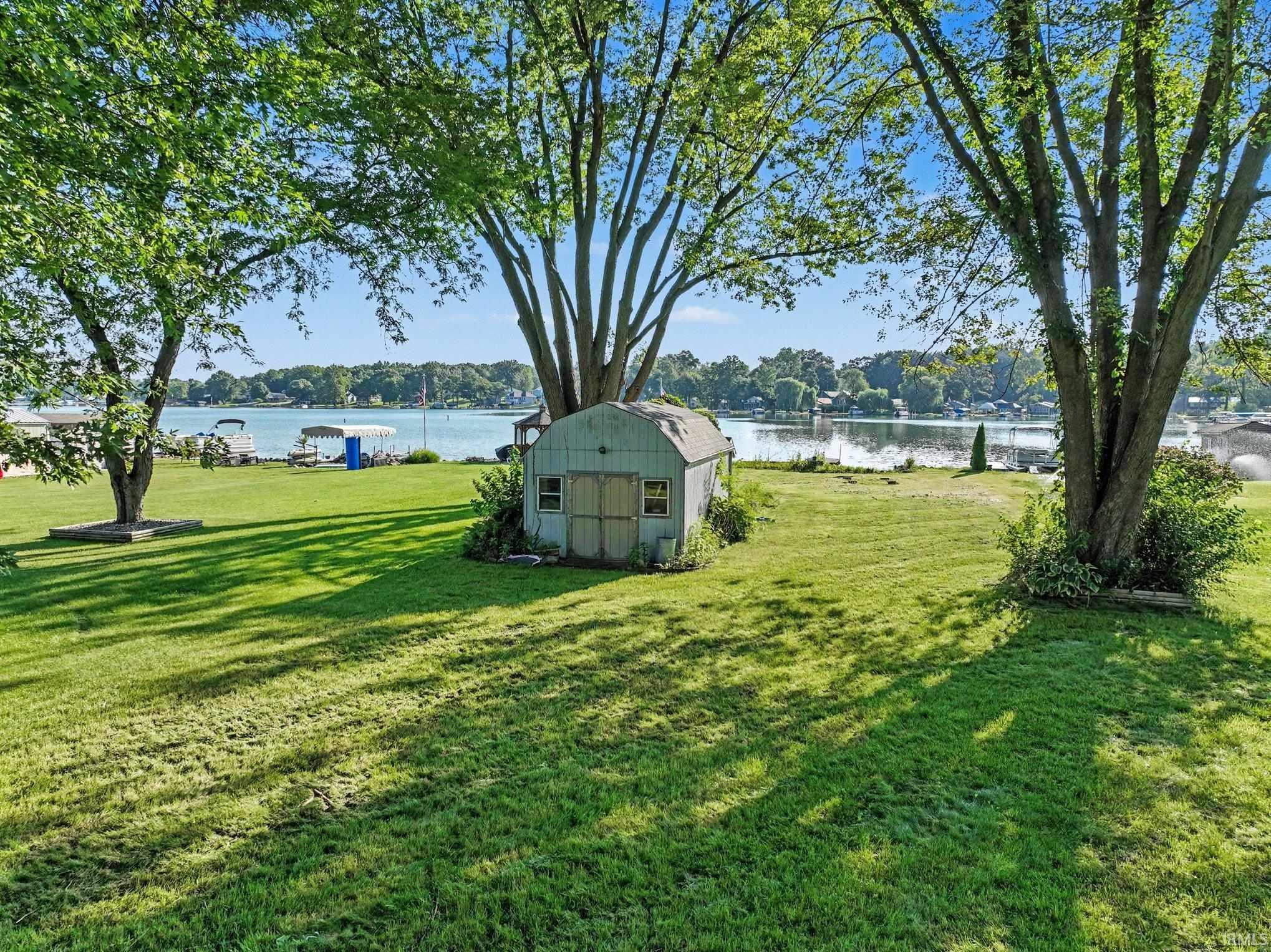 Expansive grassy yard offering waterfrontage with mature trees providing ample shade