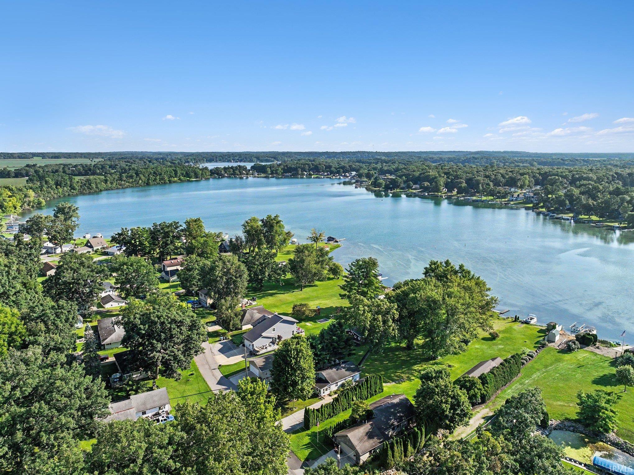 Expansive lakefront setting featuring a broad body of water, lush green trees, and multiple residential properties