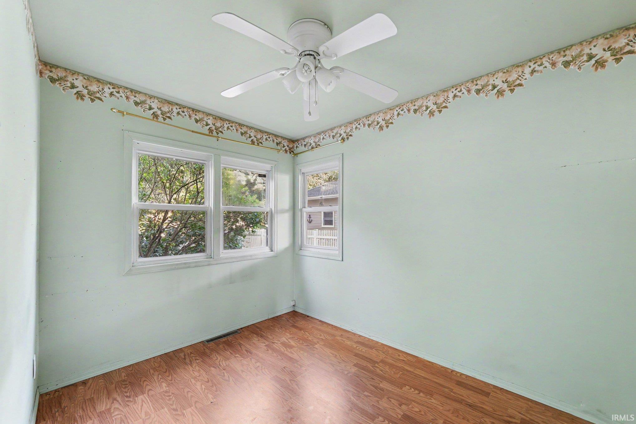 Room with wood-finish flooring, two windows, and a ceiling fan