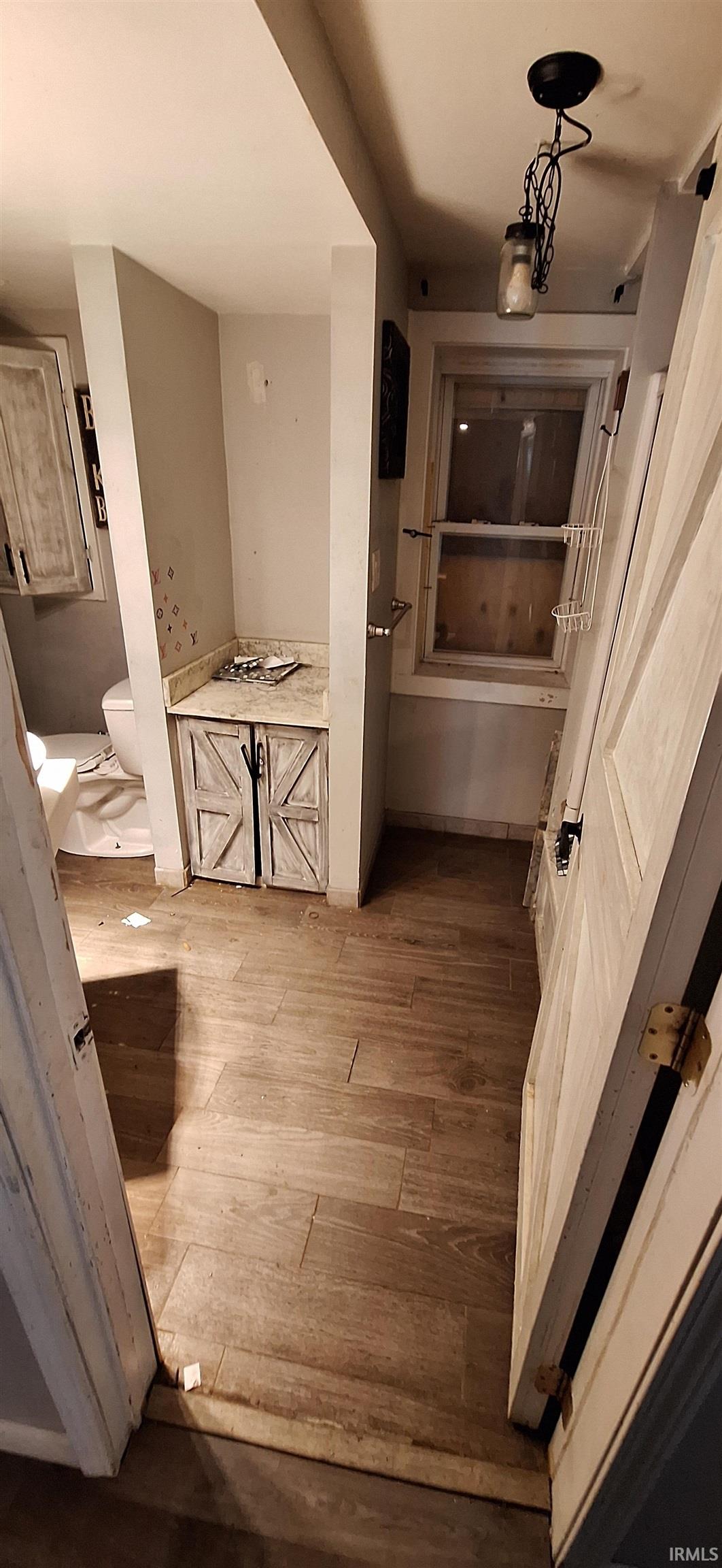 Wood-finish flooring throughout, featuring a built-in vanity with a light-toned countertop and cabinet with barn-style doors